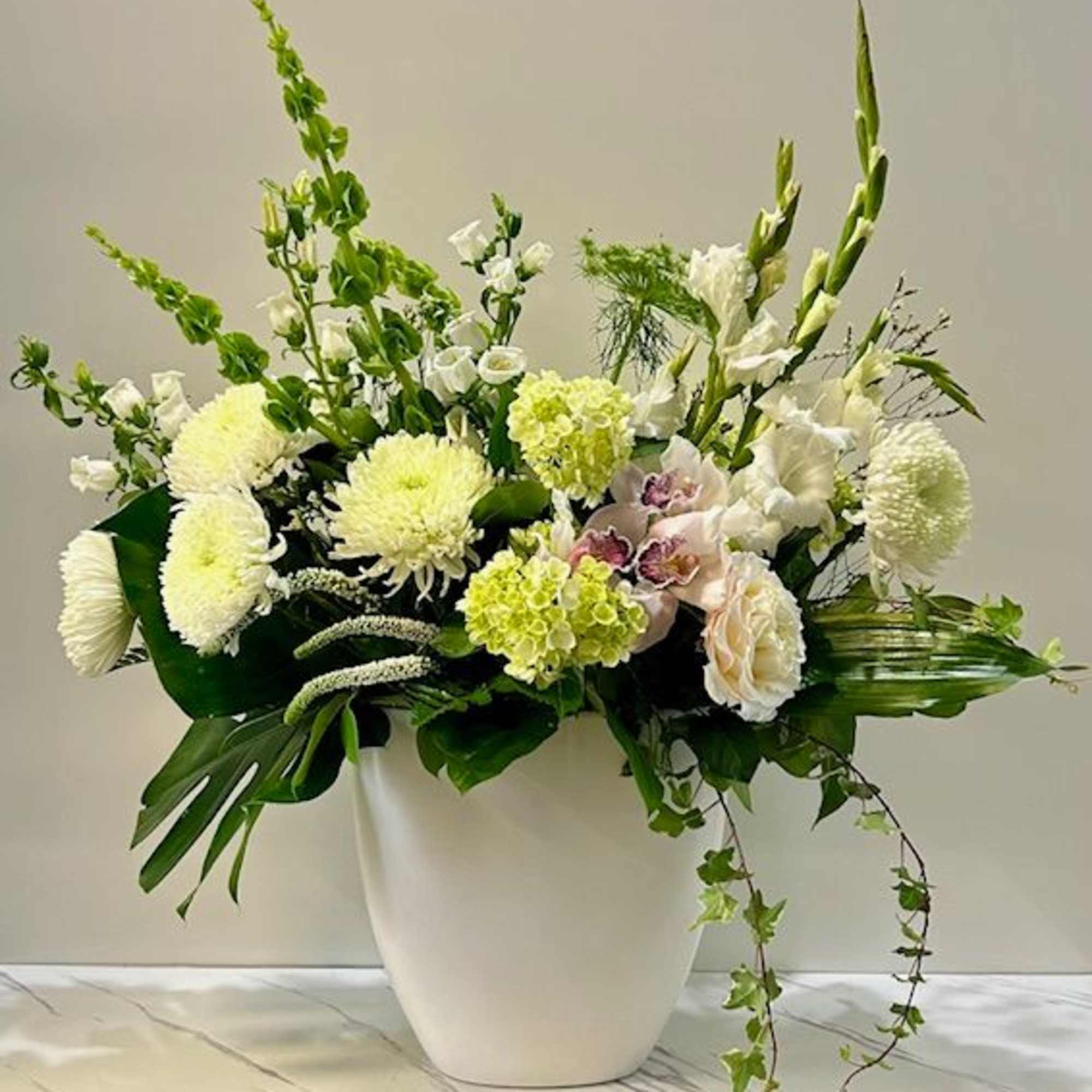White floral arrangement in a white vase with tall green spikes