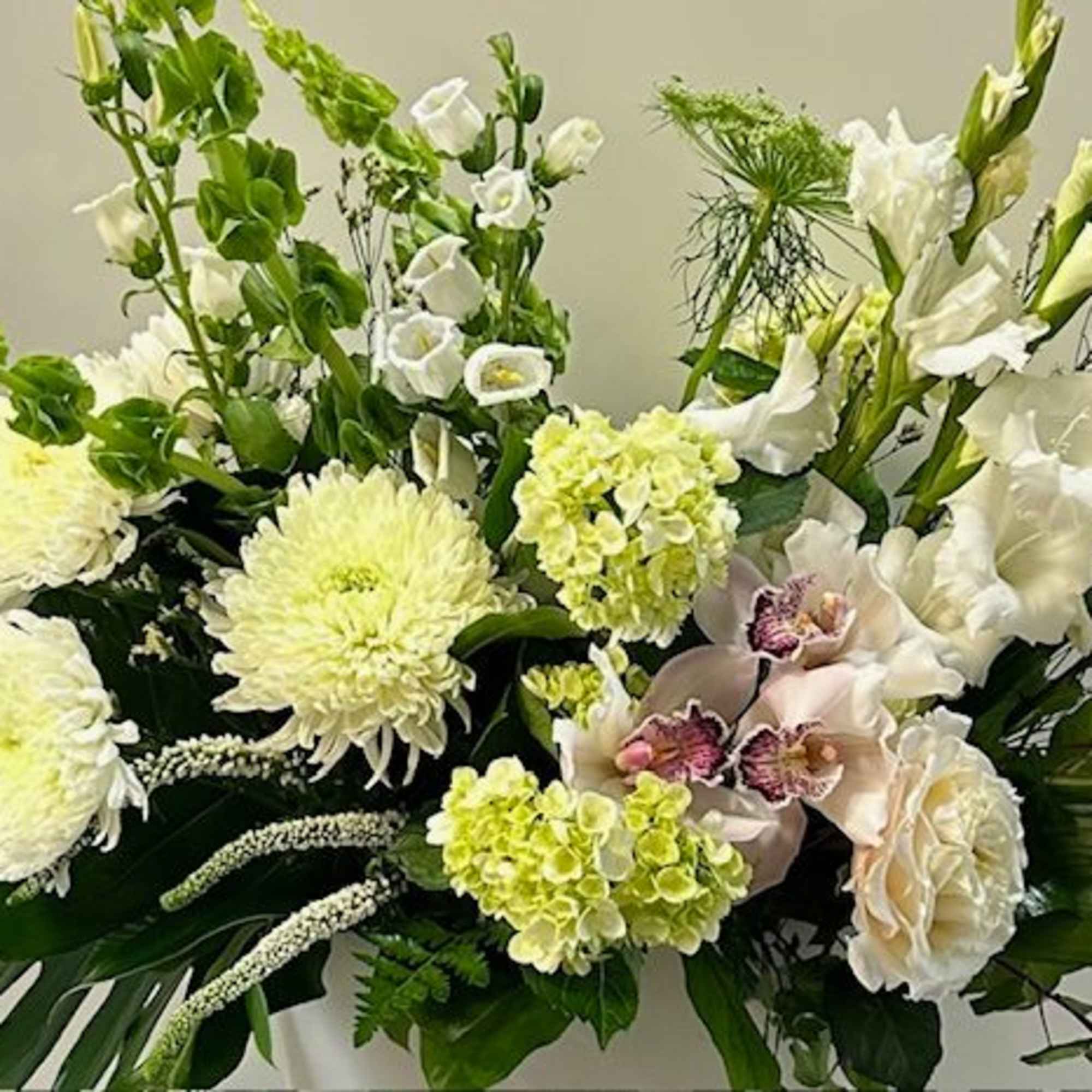 White floral arrangement with orchids, chrysanthemums, and gladiolus