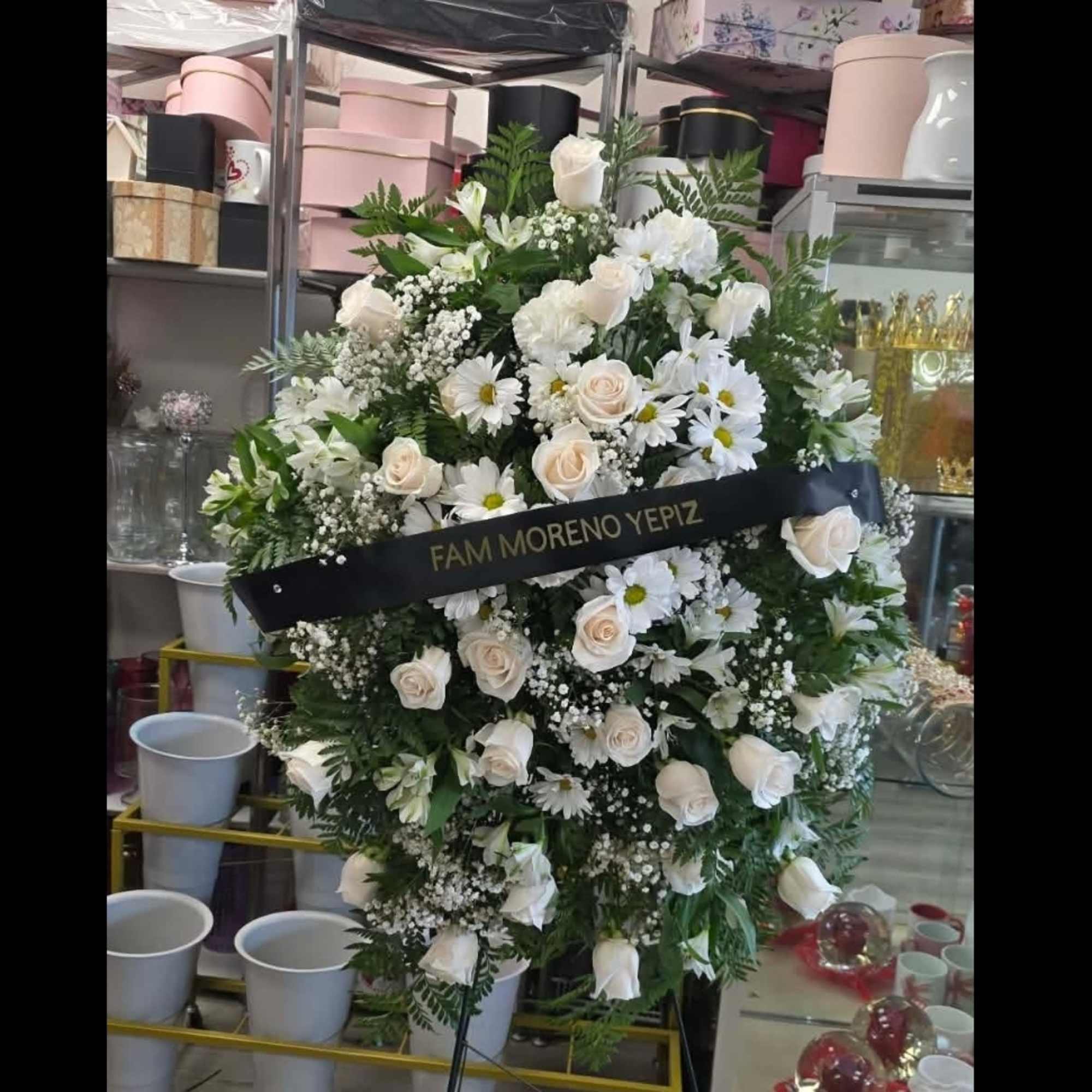 Large white floral standing spray on an easel with a black ribbon.
