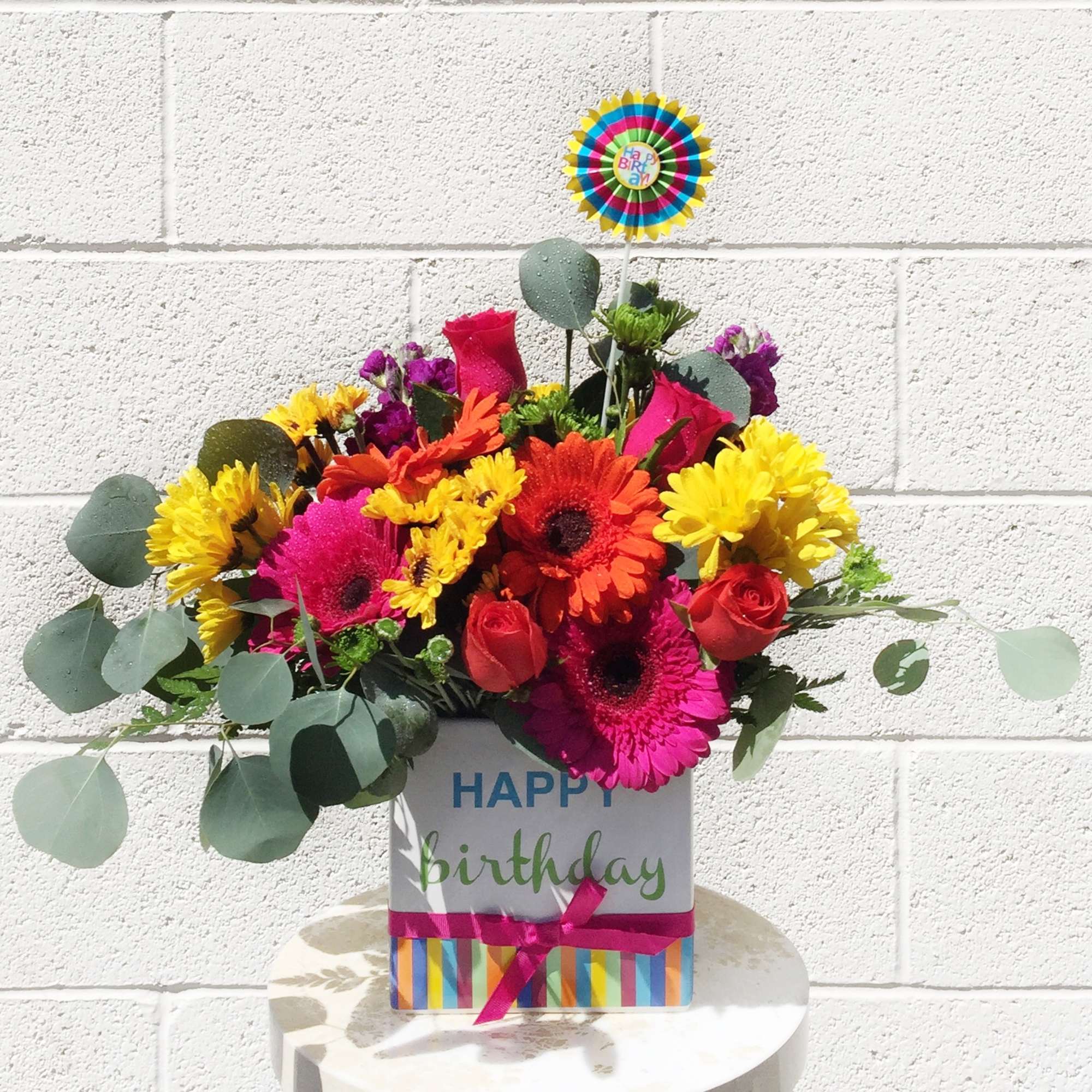Birthday flower arrangement in a decorated gift box with a topper