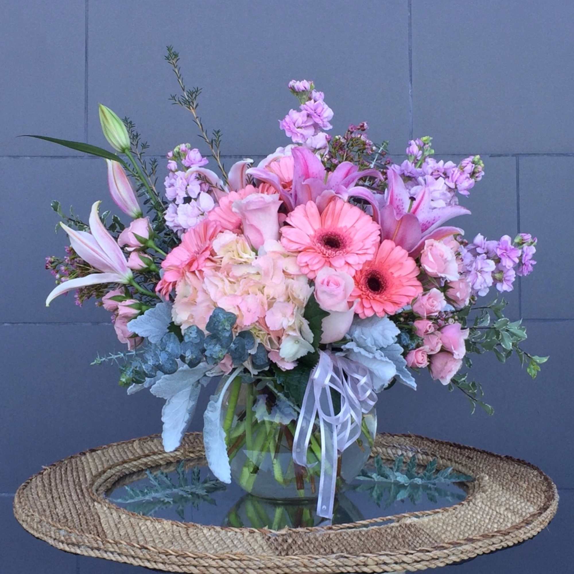 Pink and lavender bouquet with lilies, gerbera daisies, and roses in a glass vase