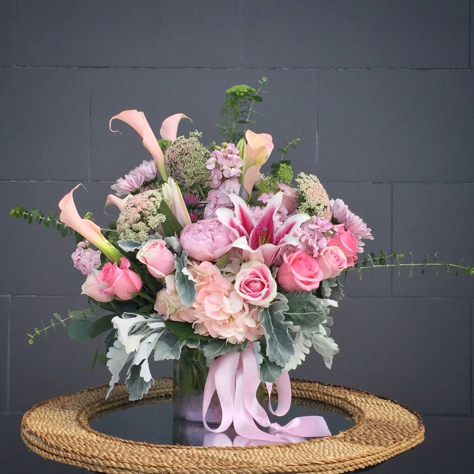 Pink and white floral arrangement in a glass vase with a ribbon