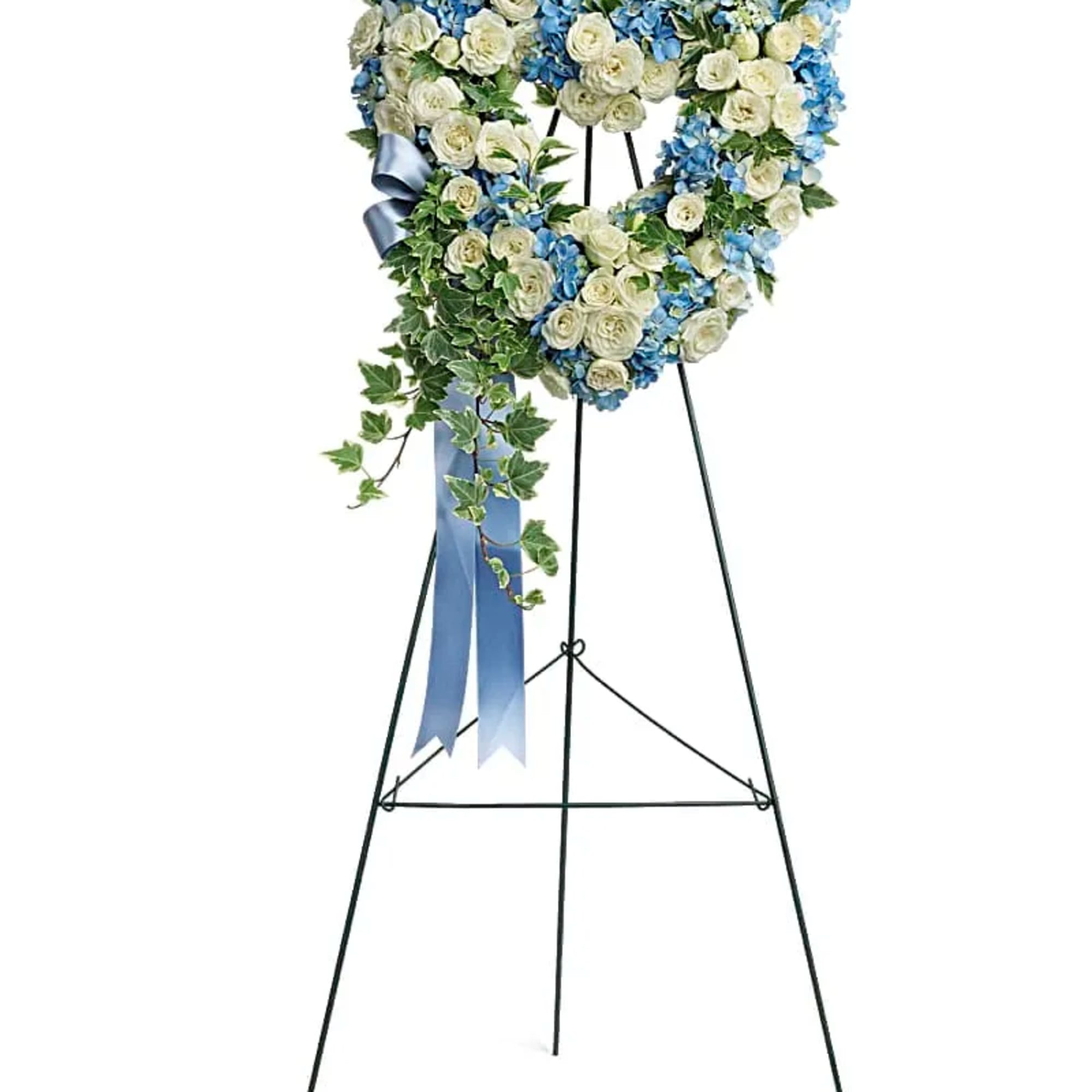 Heart-shaped wreath of white roses and blue flowers on a tall stand with blue ribbon and ivy accents