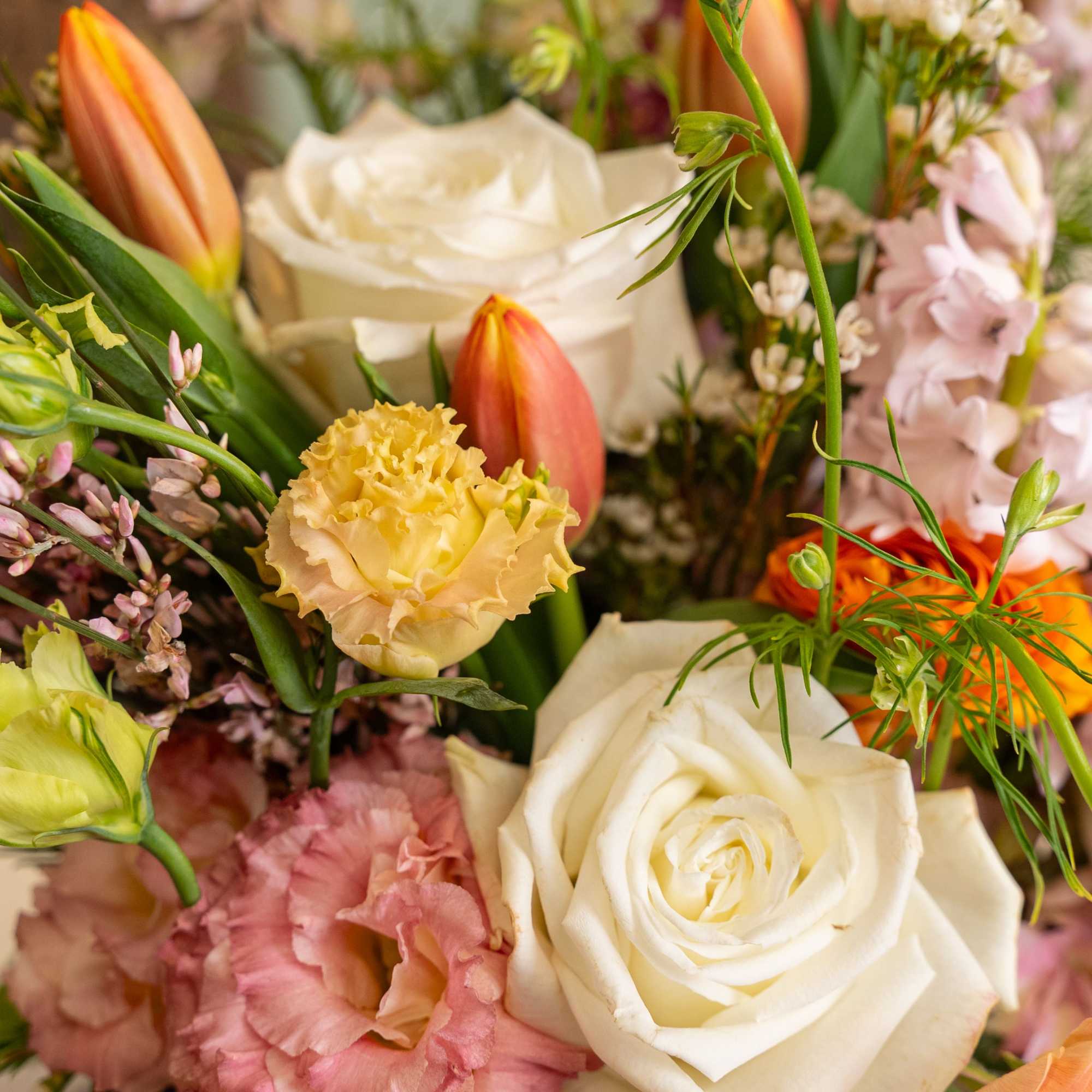 Mixed bouquet with white roses, peach carnations, tulips, and pastel blooms in soft spring colors