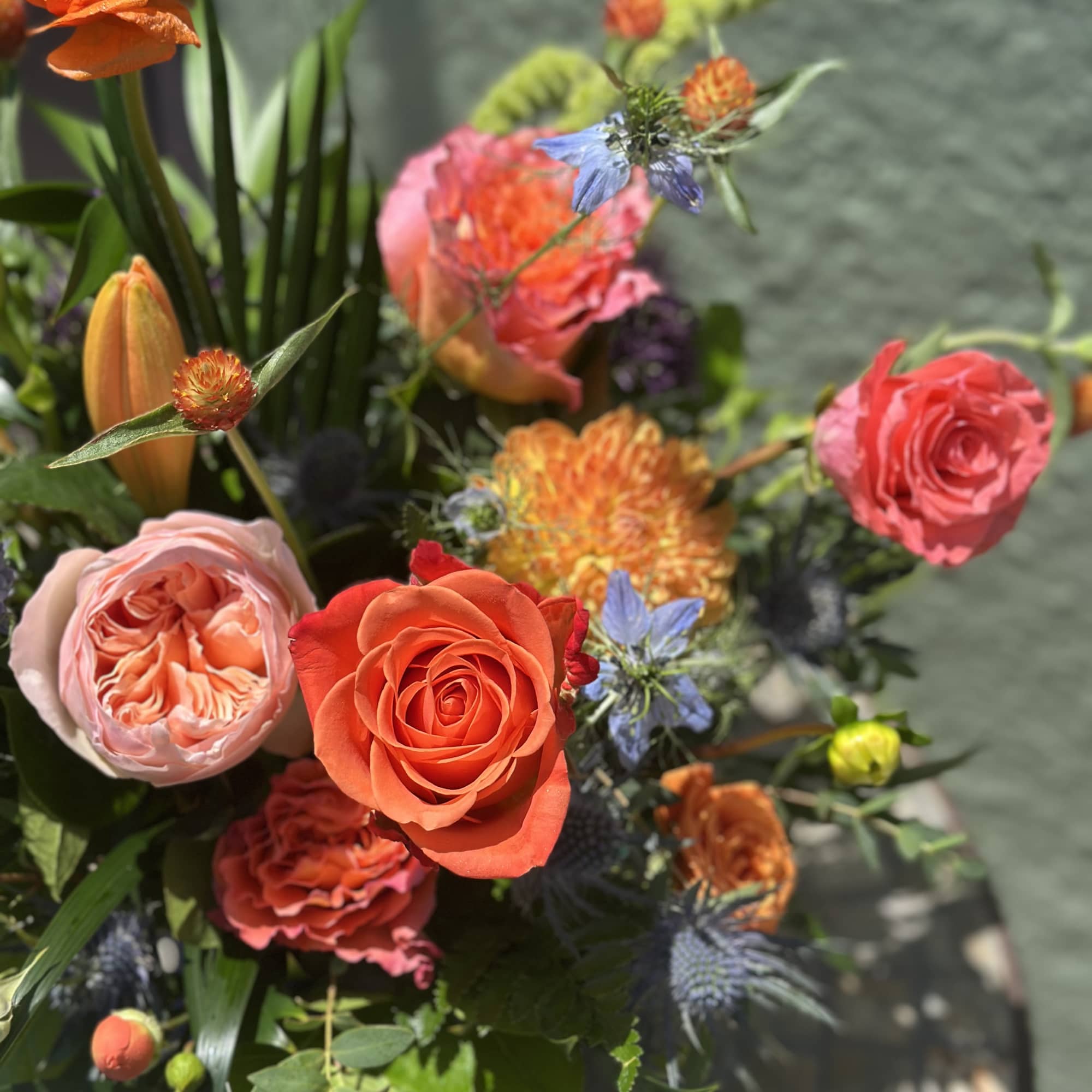 Mixed bouquet with orange and pink roses and blue accent flowers