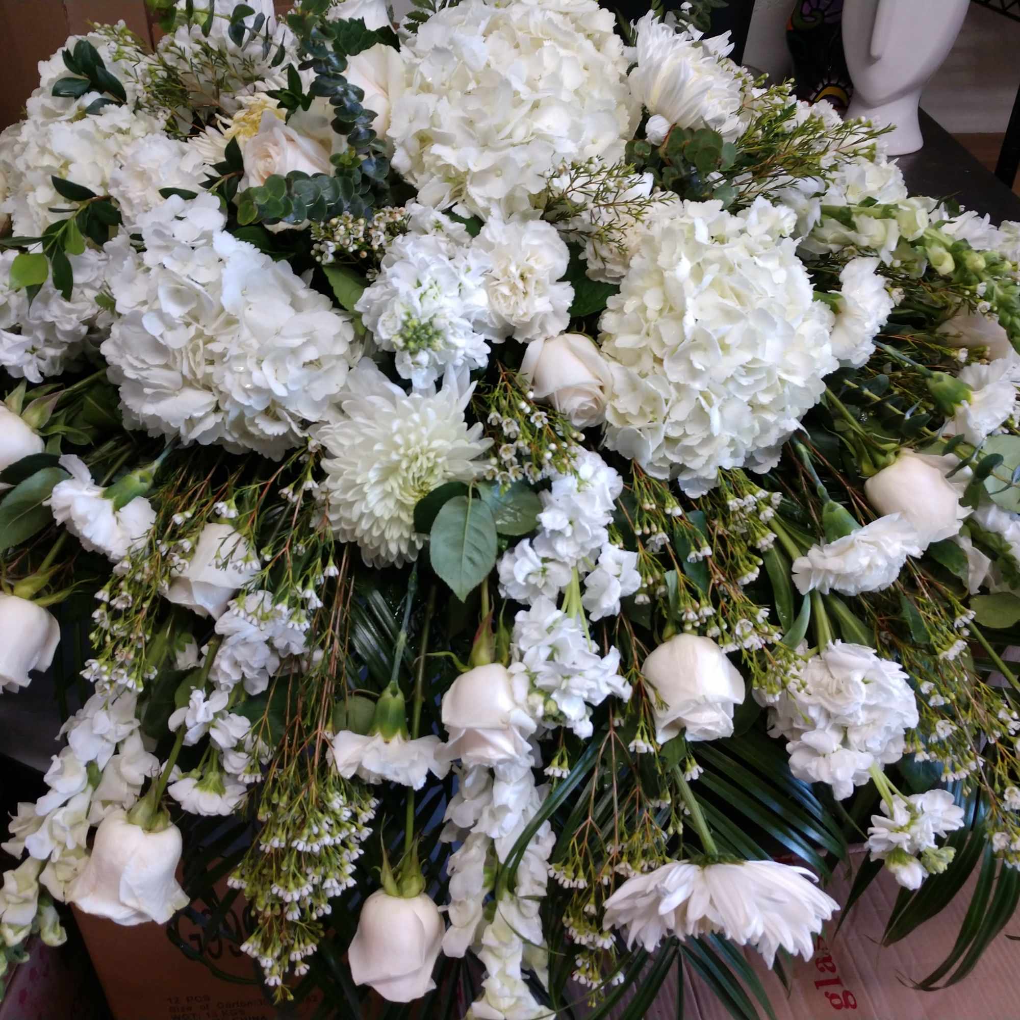 Large white floral arrangement with roses, hydrangeas, and daisies