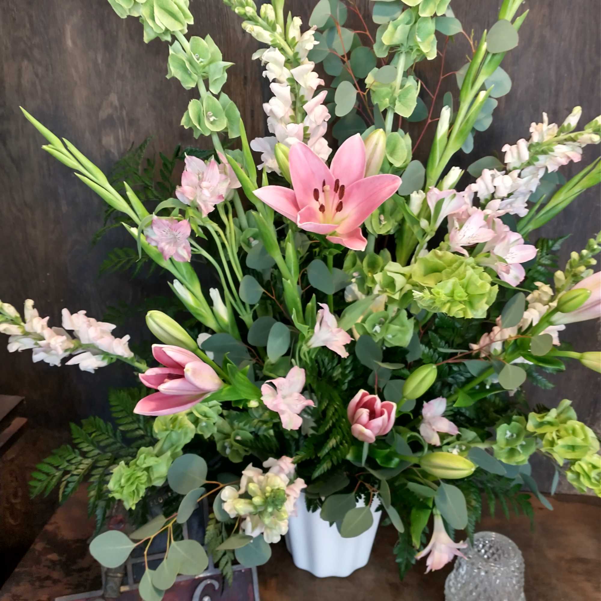 Pink lilies and pale blooms arranged in a white vase