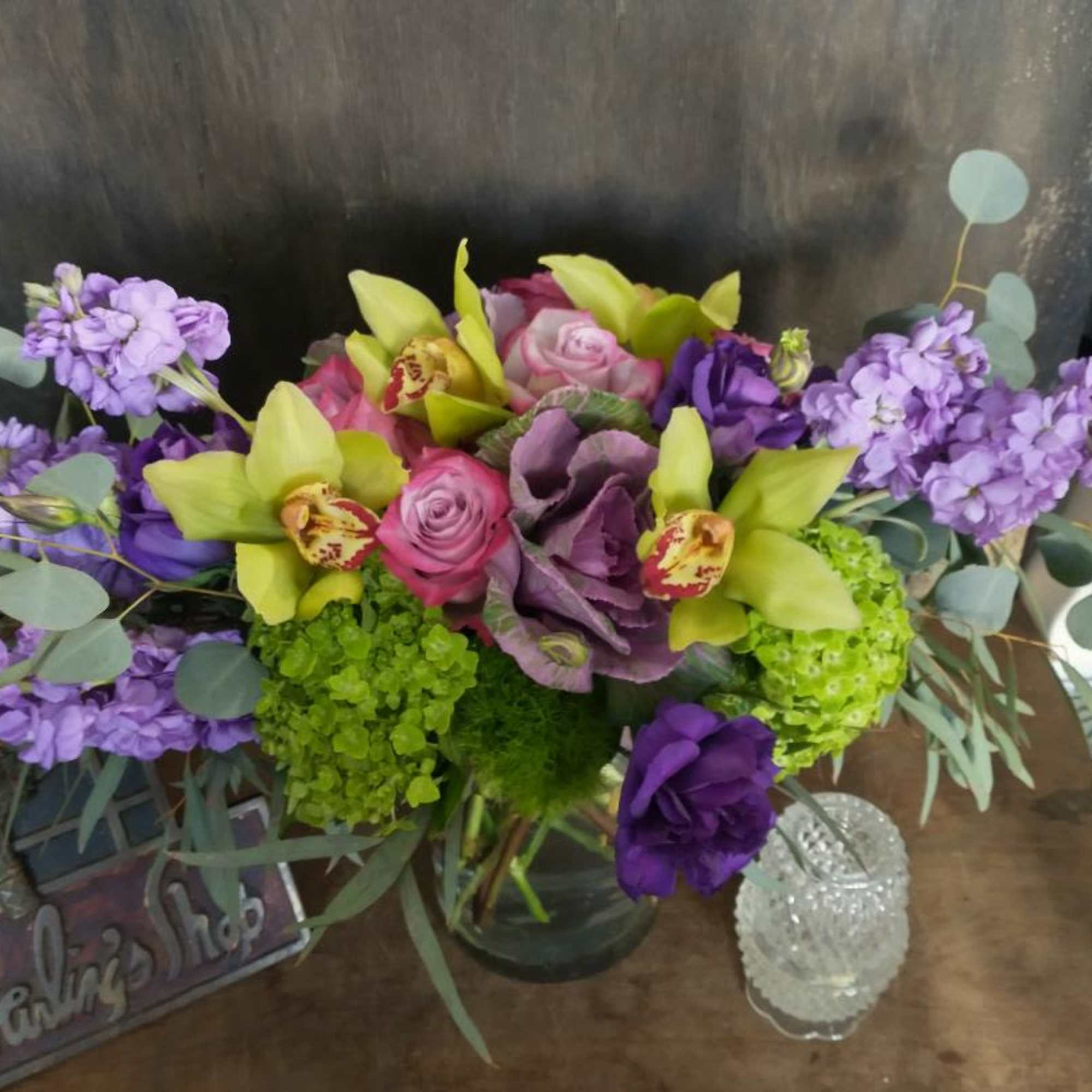 Purple and green floral arrangement in a glass vase