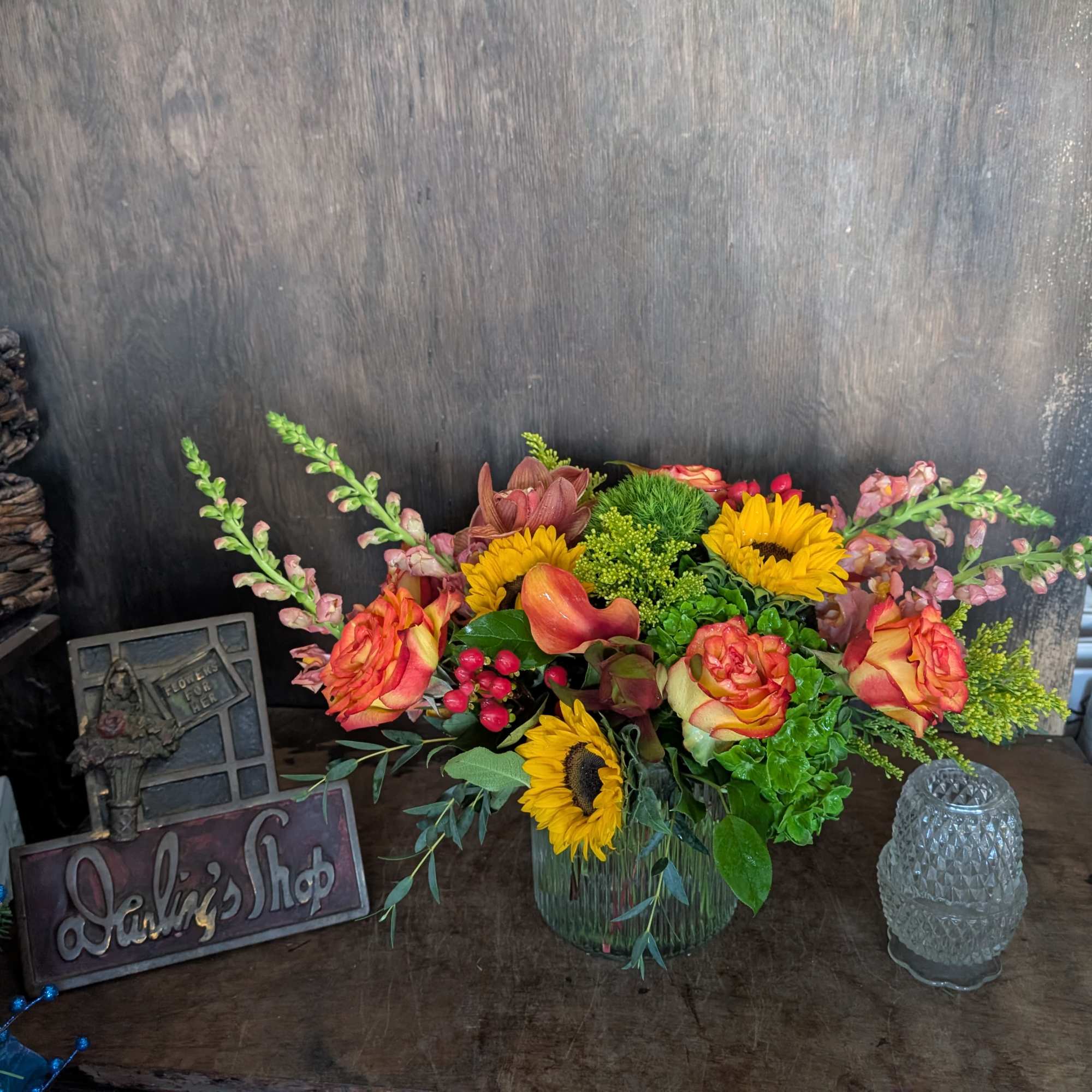 Mixed bouquet with sunflowers, roses, and calla lilies in a glass vase
