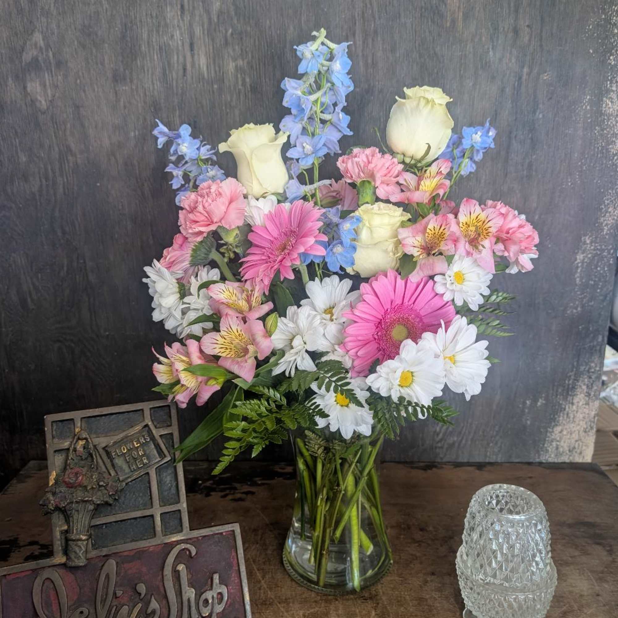 Mixed bouquet in a clear glass vase with pink, white, and blue flowers