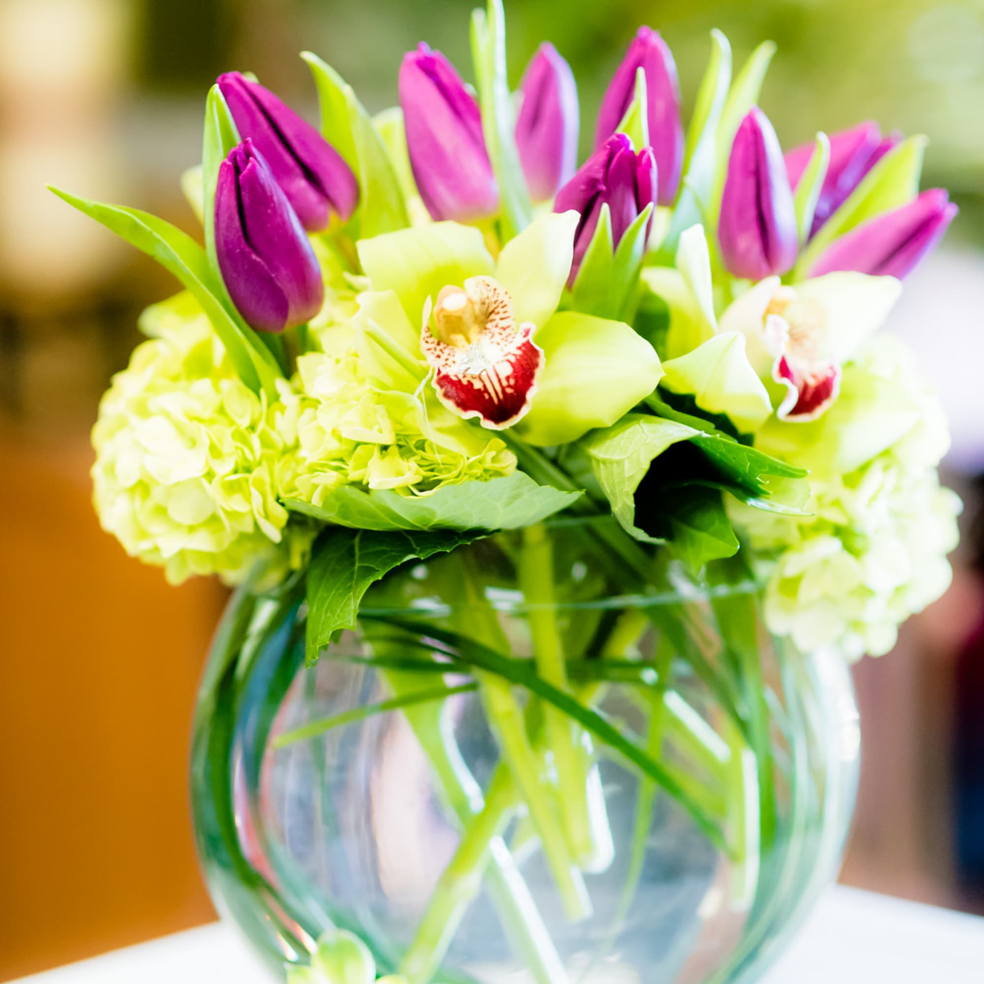 Bouquet of purple tulips and pale green orchids in a glass vase