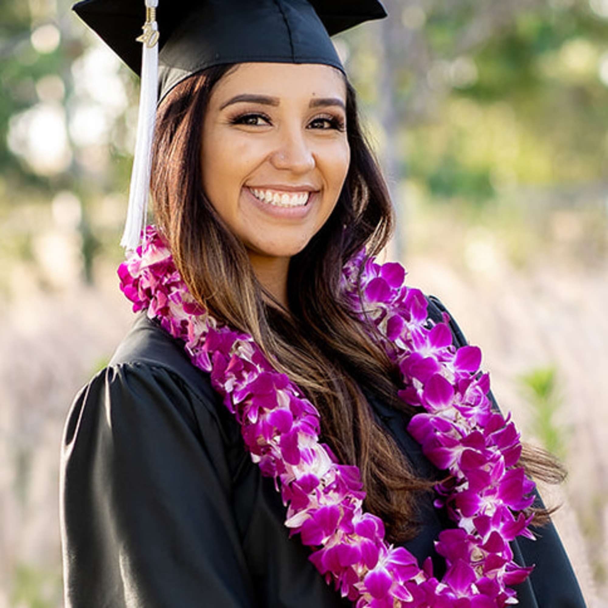Graduate in cap and gown wearing a purple orchid lei