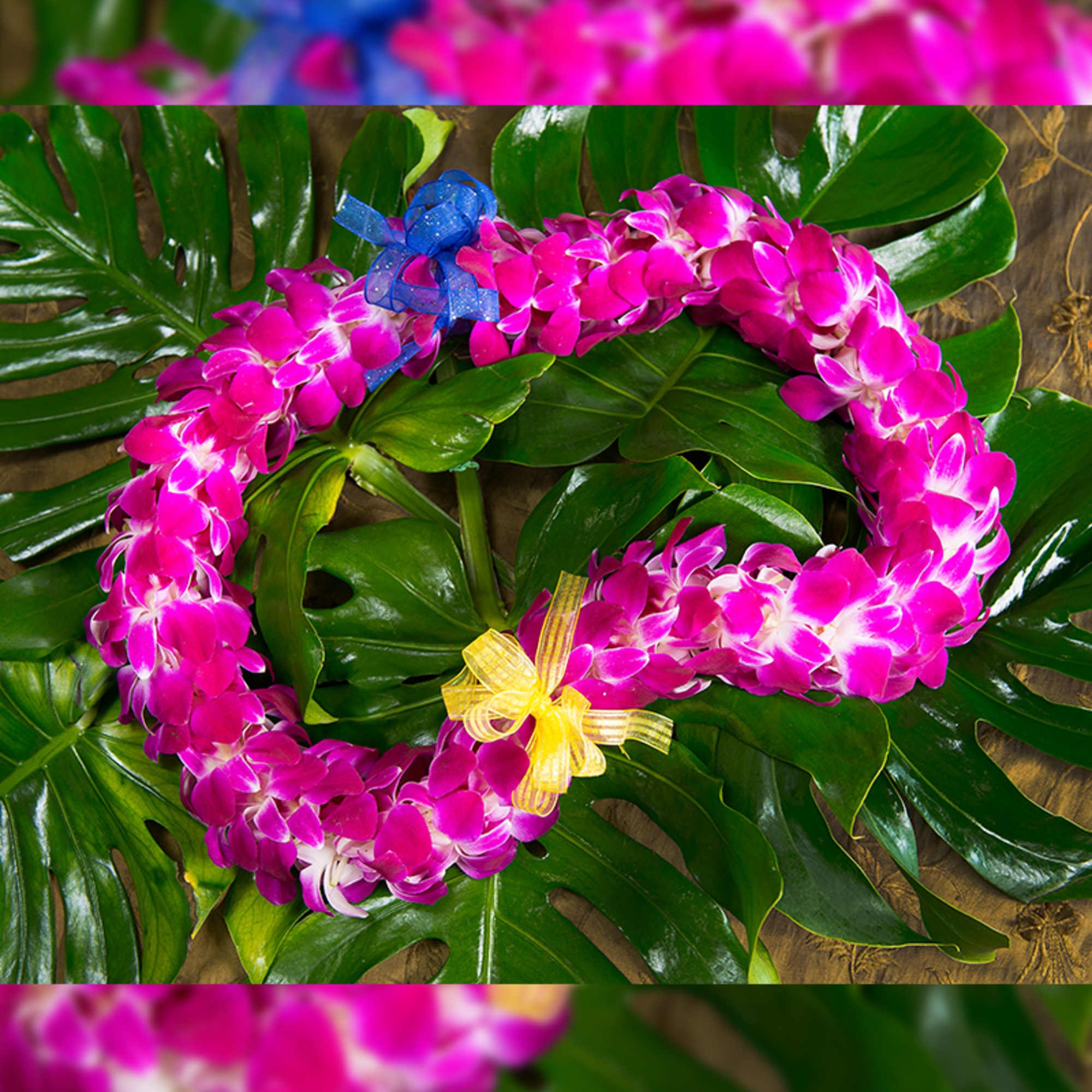 Two pink orchid leis on large green leaves