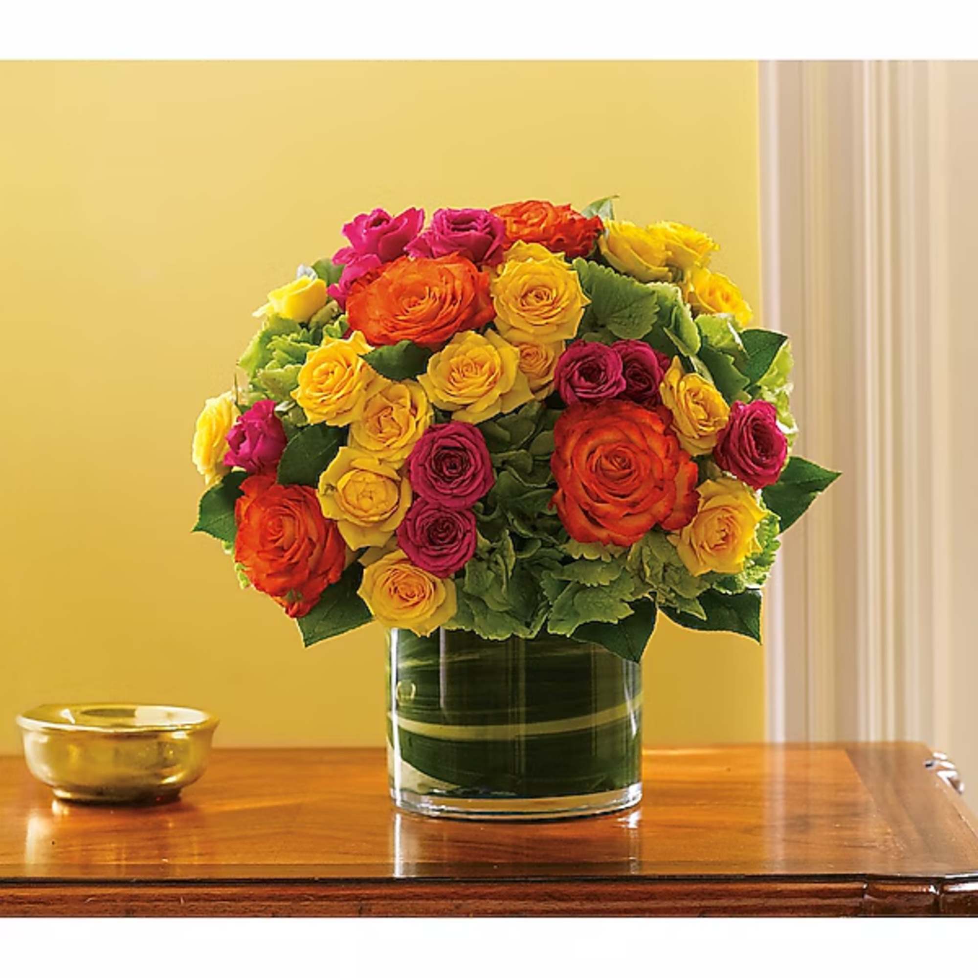 Bouquet of yellow, orange, and pink roses in a glass vase