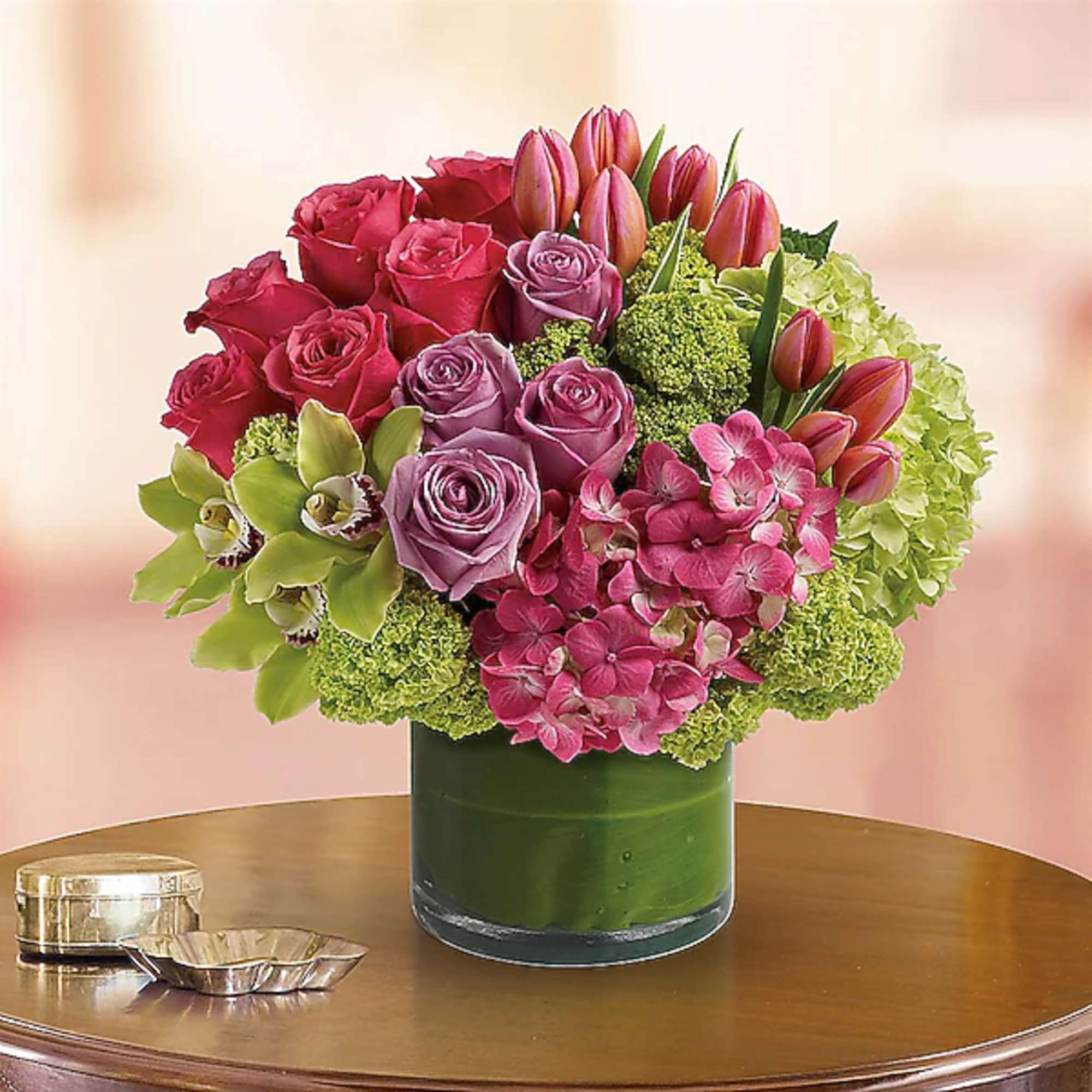Pink and lavender roses with tulips and hydrangeas in a glass vase