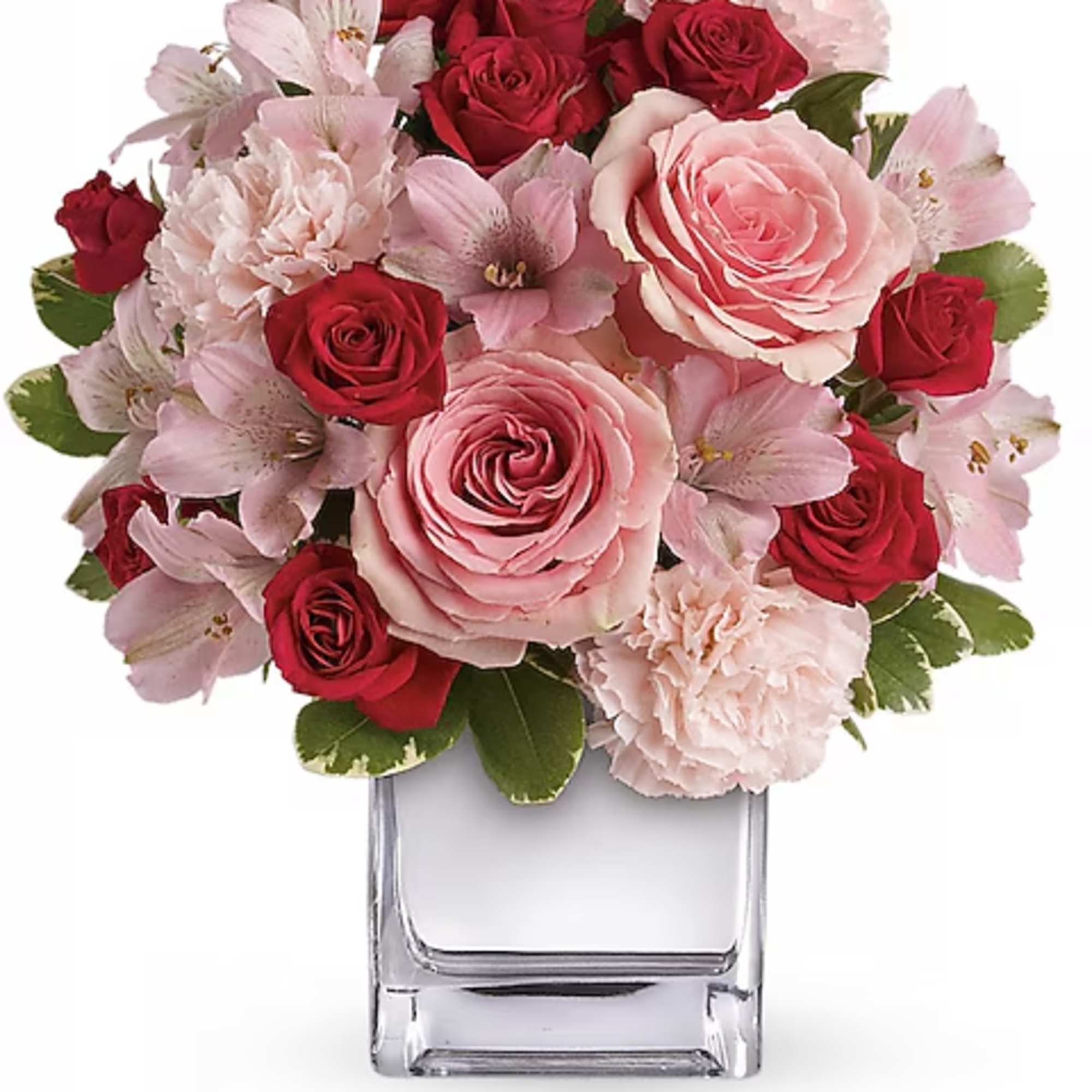 Pink and red roses with pale pink flowers in a clear square vase