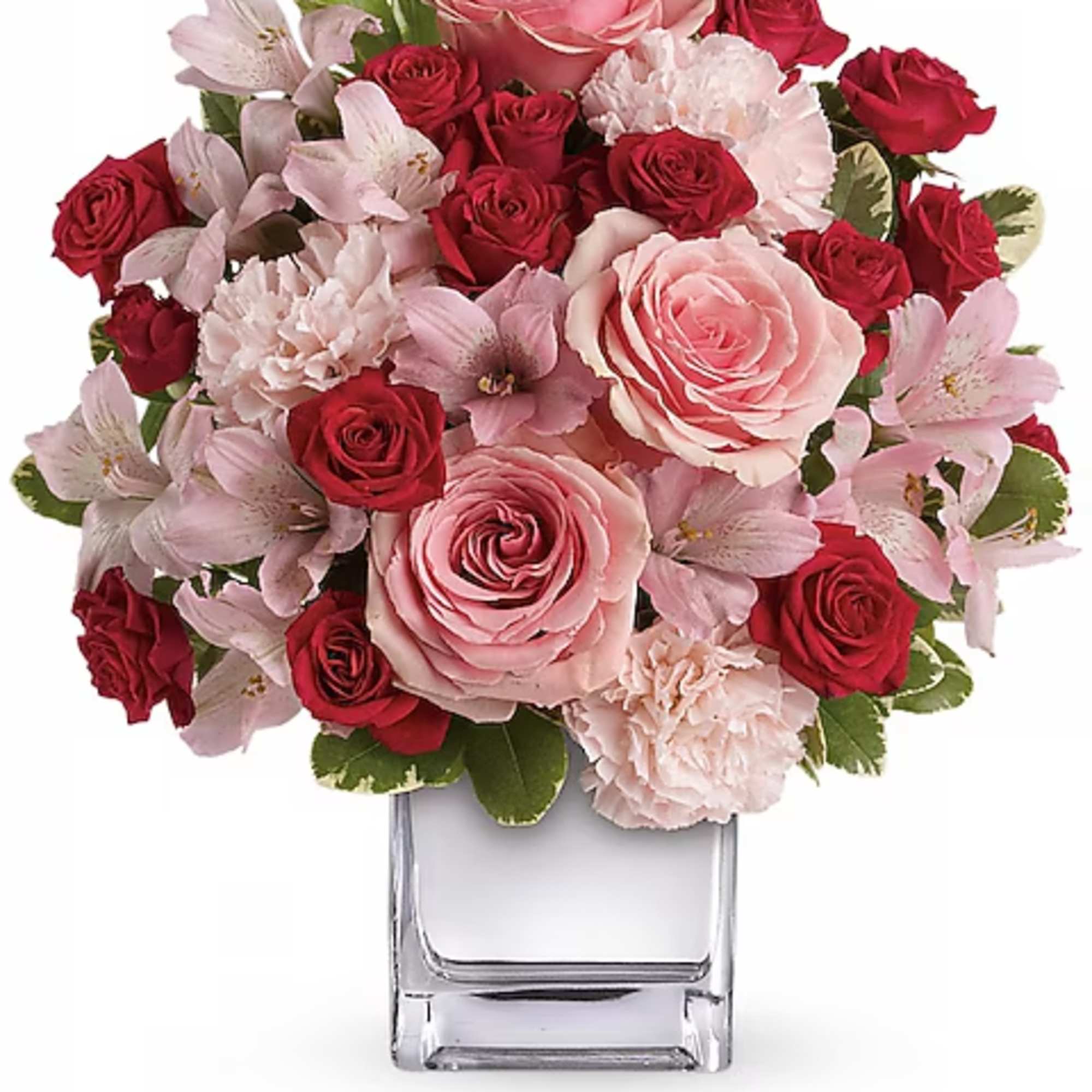Pink and red roses with pale pink flowers in a clear glass vase