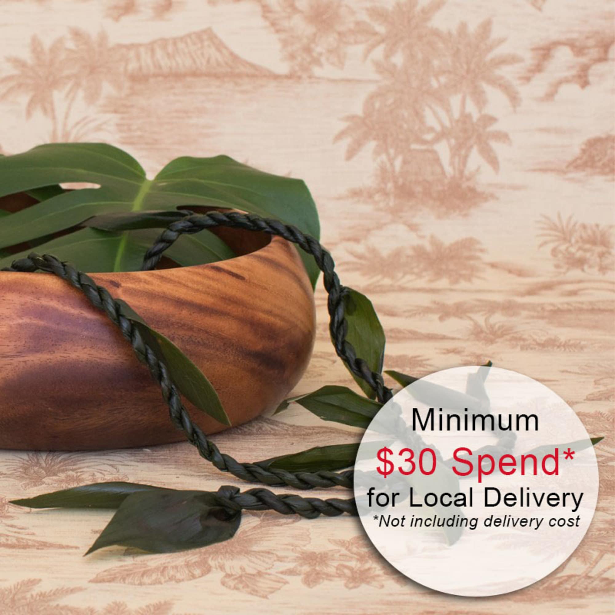 Wooden bowl with braided green leaf lei on a tropical patterned background