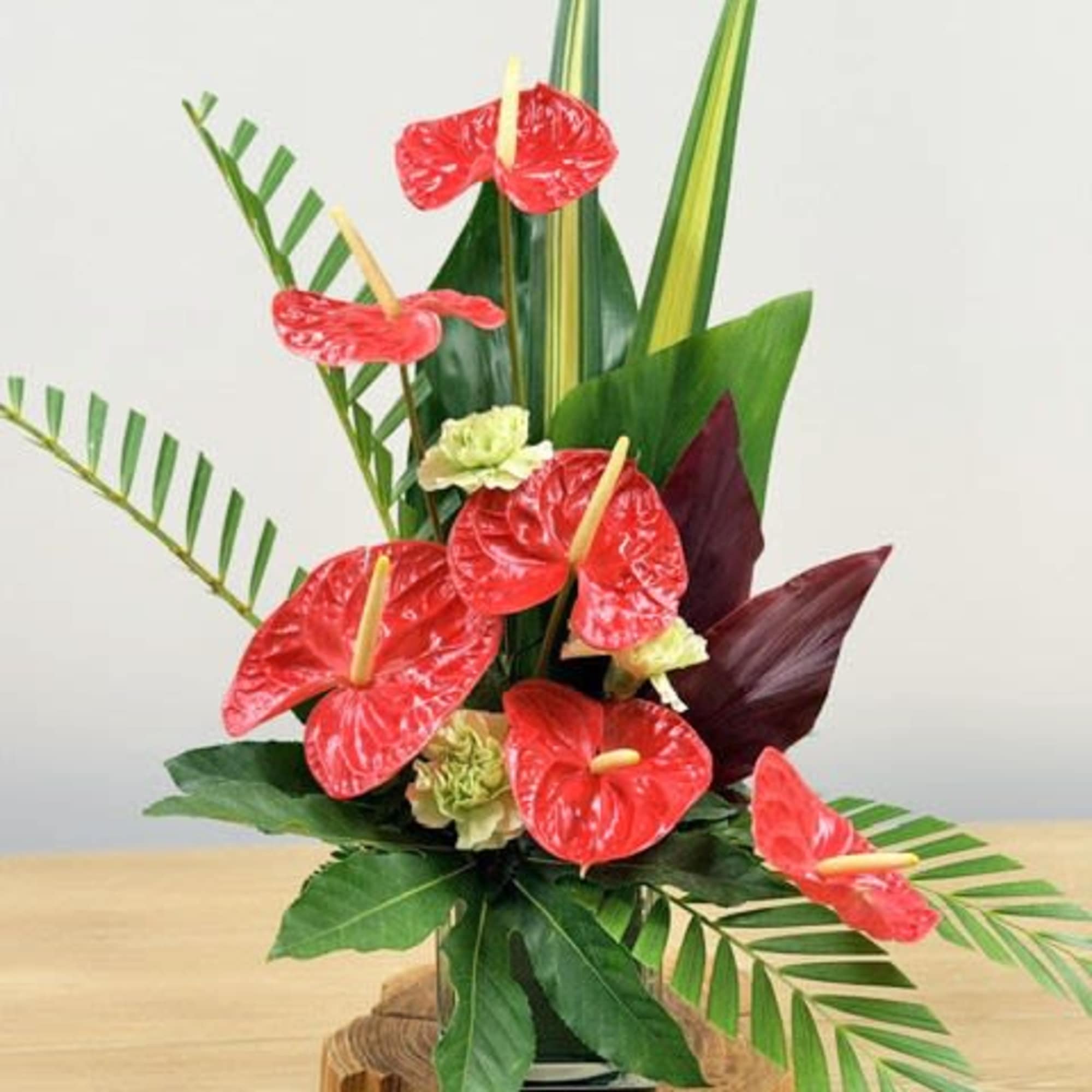 Glossy red anthuriums and architectural tropical foliage give this flower arrangement an, photo 2 of 2