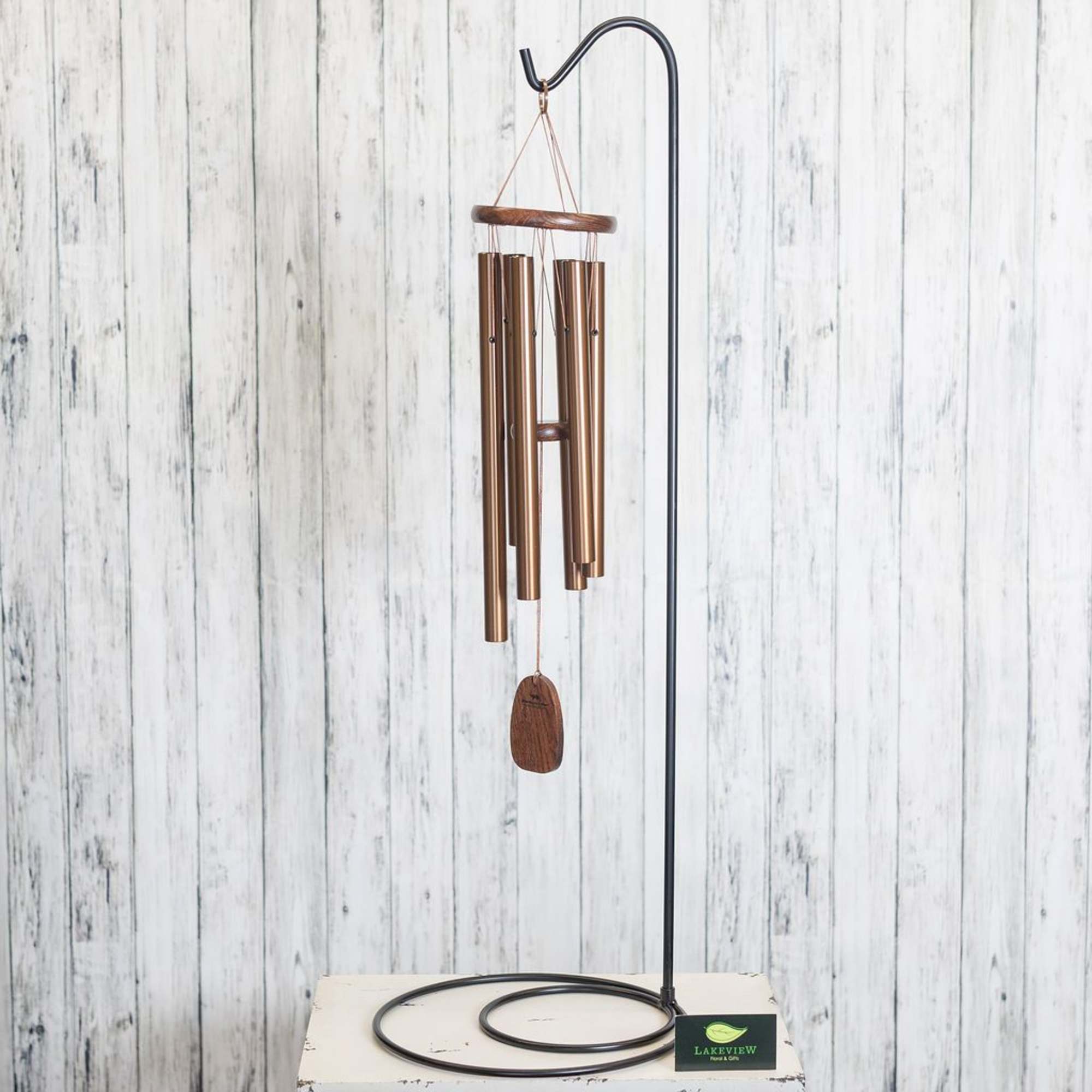 Copper wind chime hanging from a black metal stand