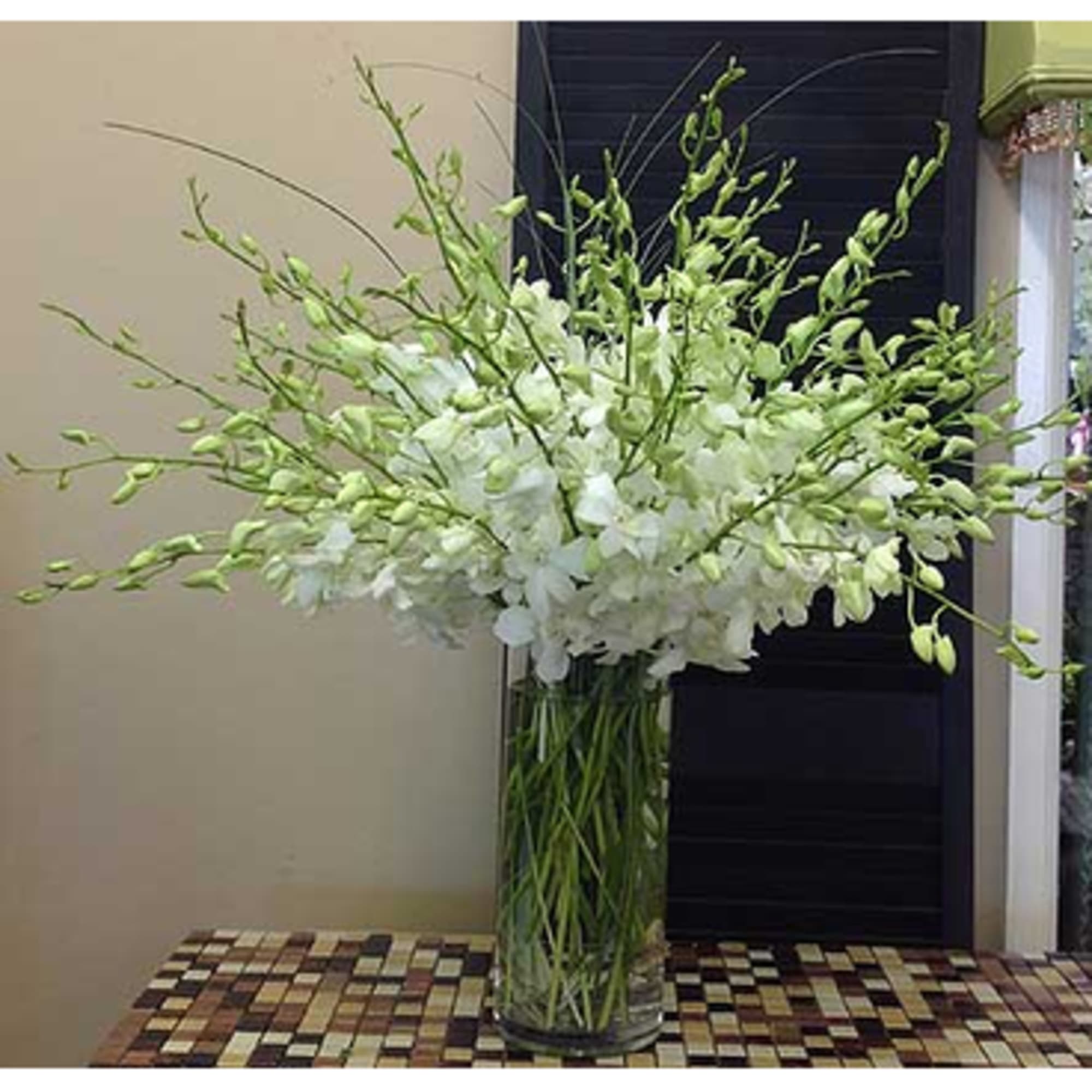 Tall white floral arrangement in a clear glass vase