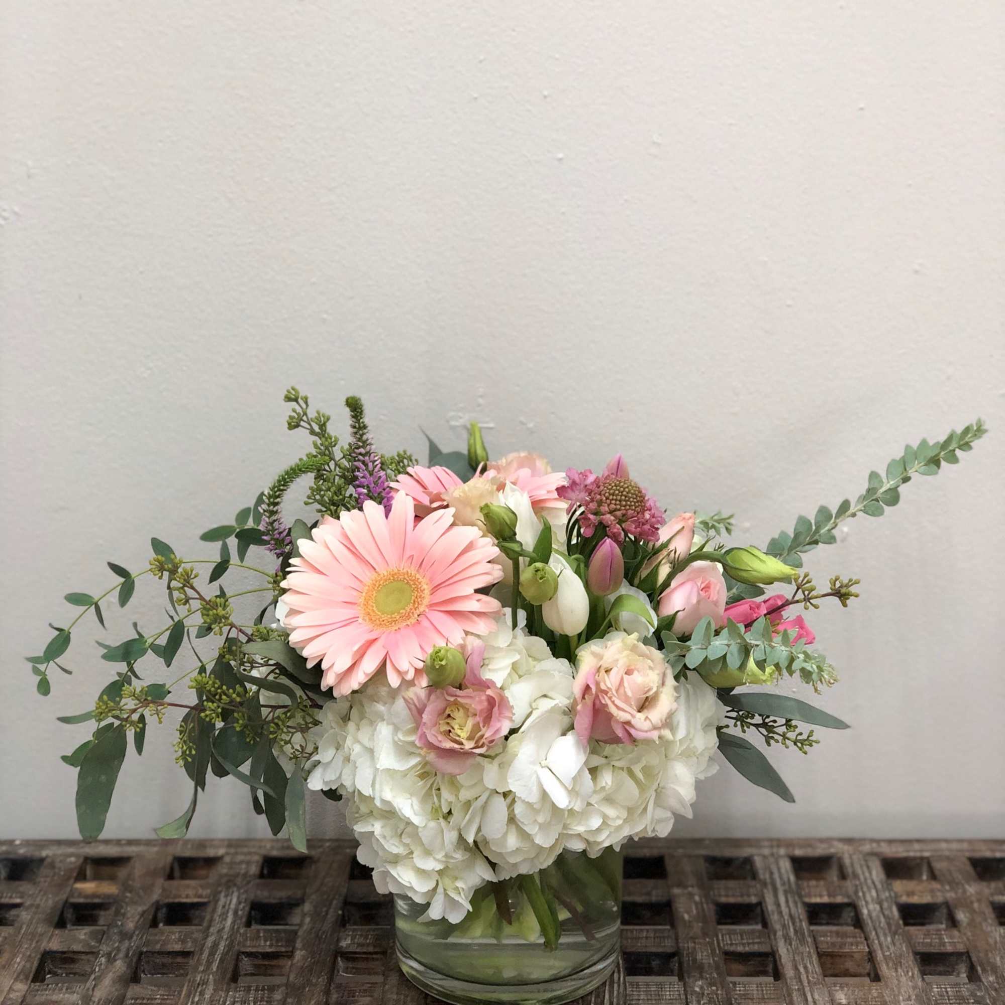 Pink gerbera daisies and white hydrangeas in a glass vase