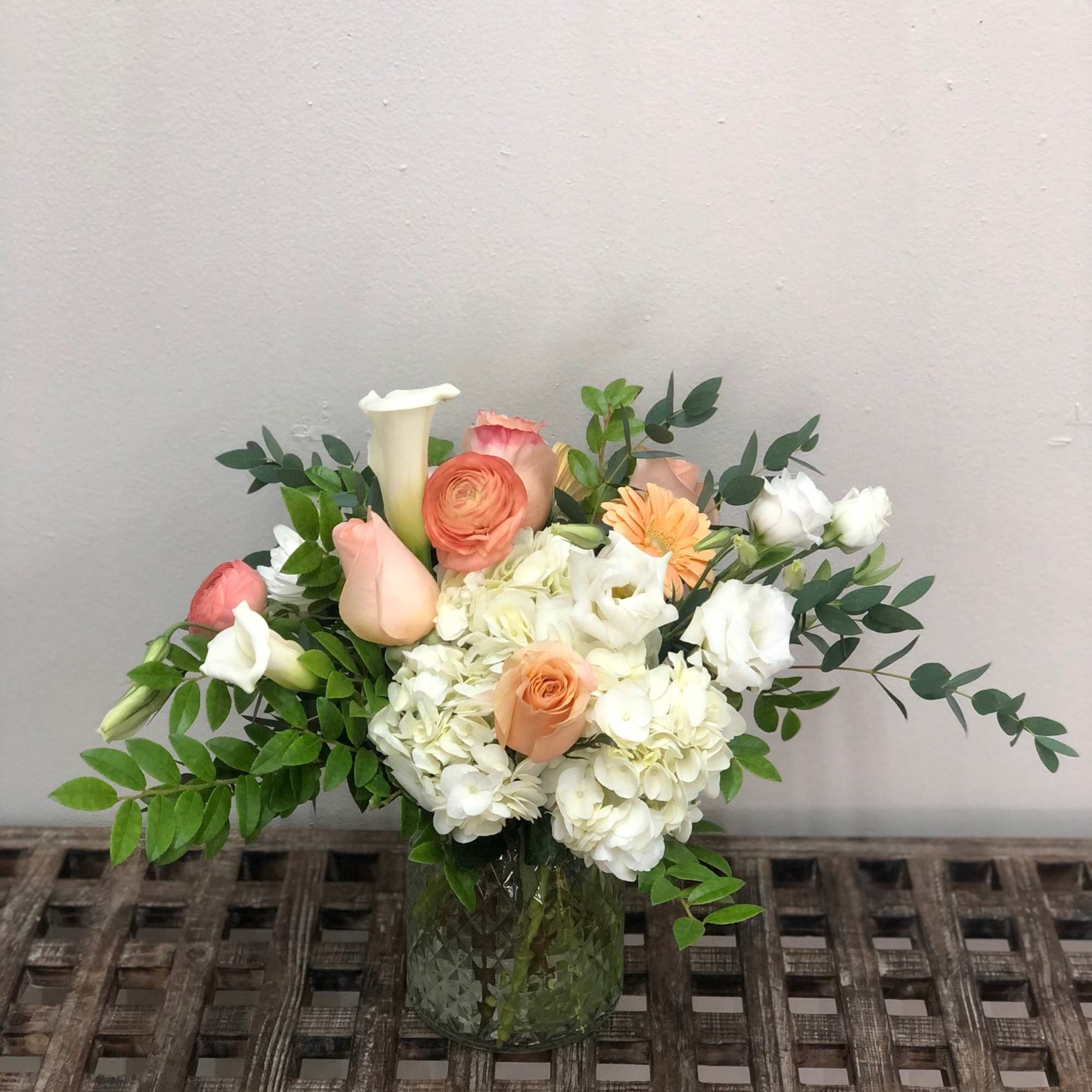 Mixed bouquet of peach, white, and pink flowers in a glass vase