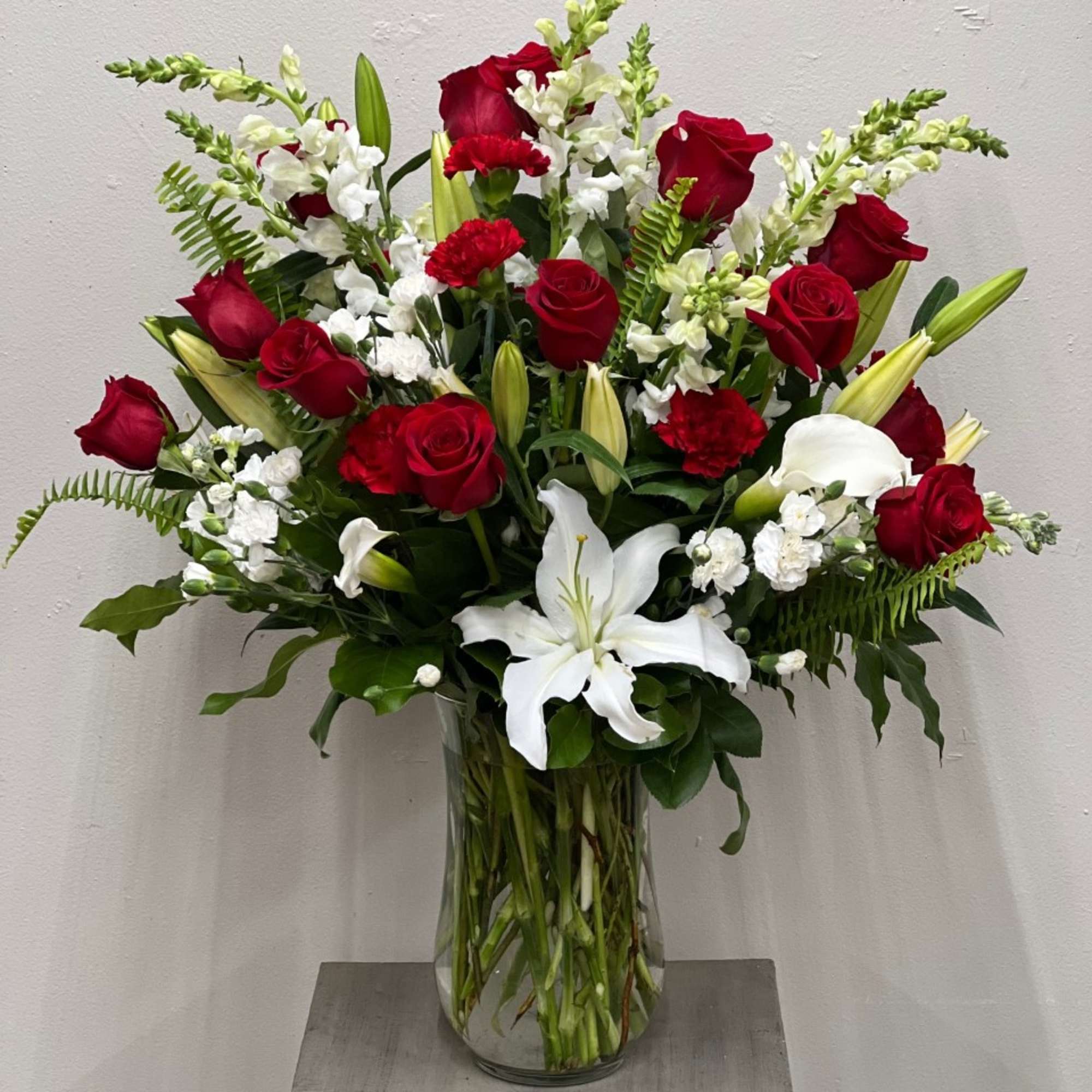 Red roses and white lilies arranged in a clear glass vase