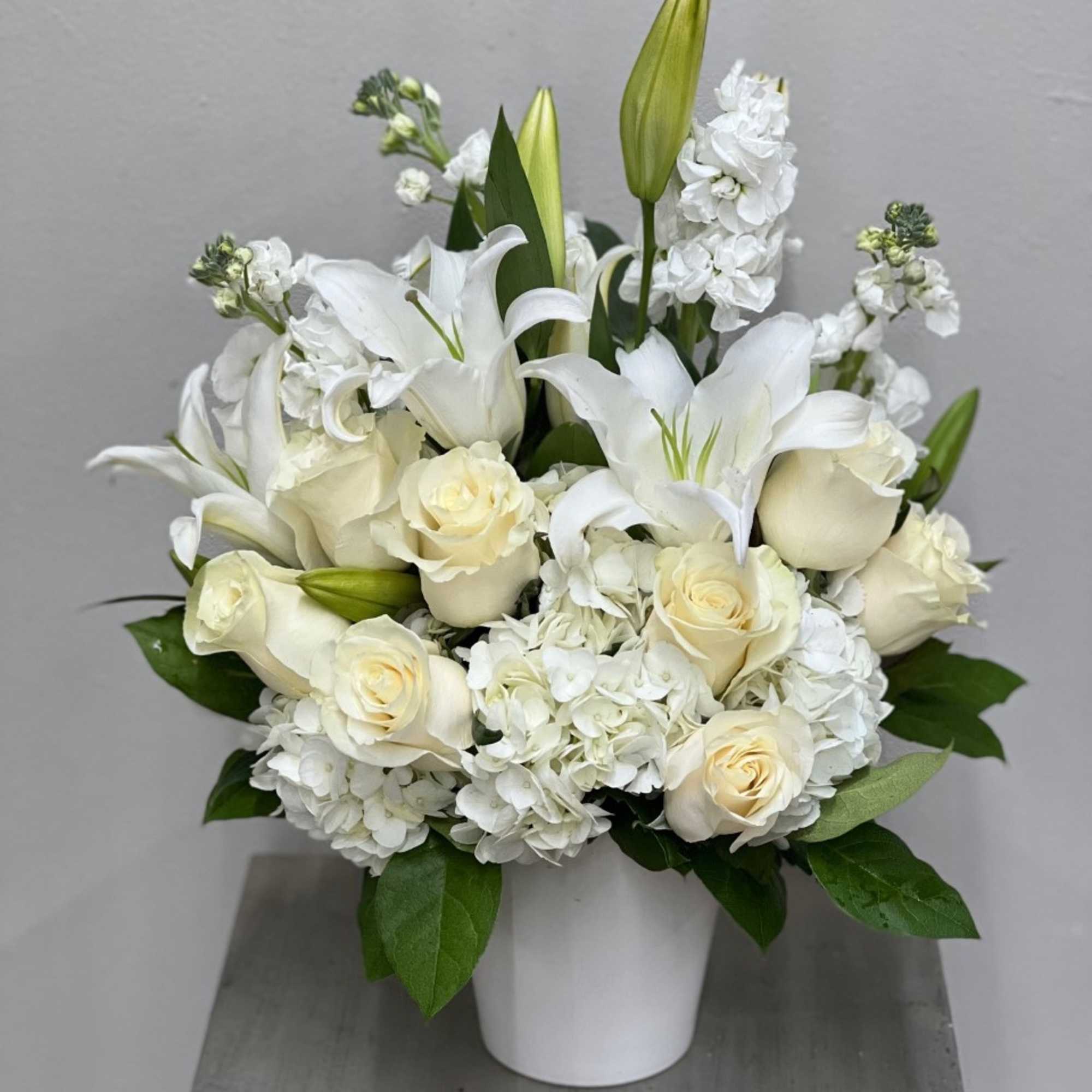 White roses and lilies arranged in a white vase