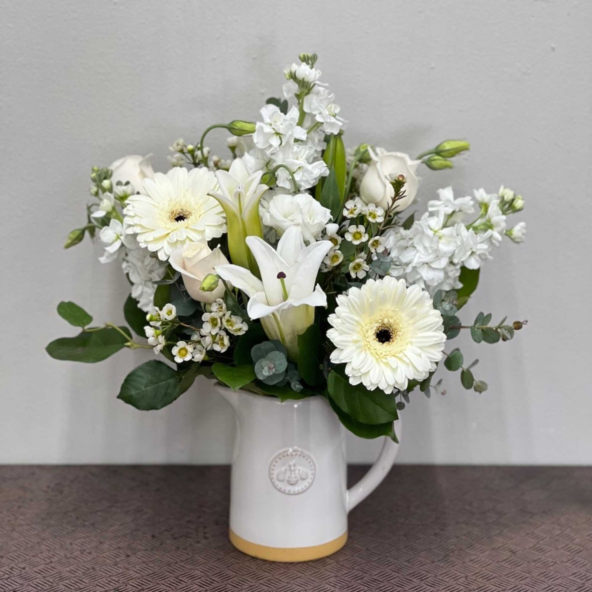 White floral arrangement in a ceramic pitcher vase