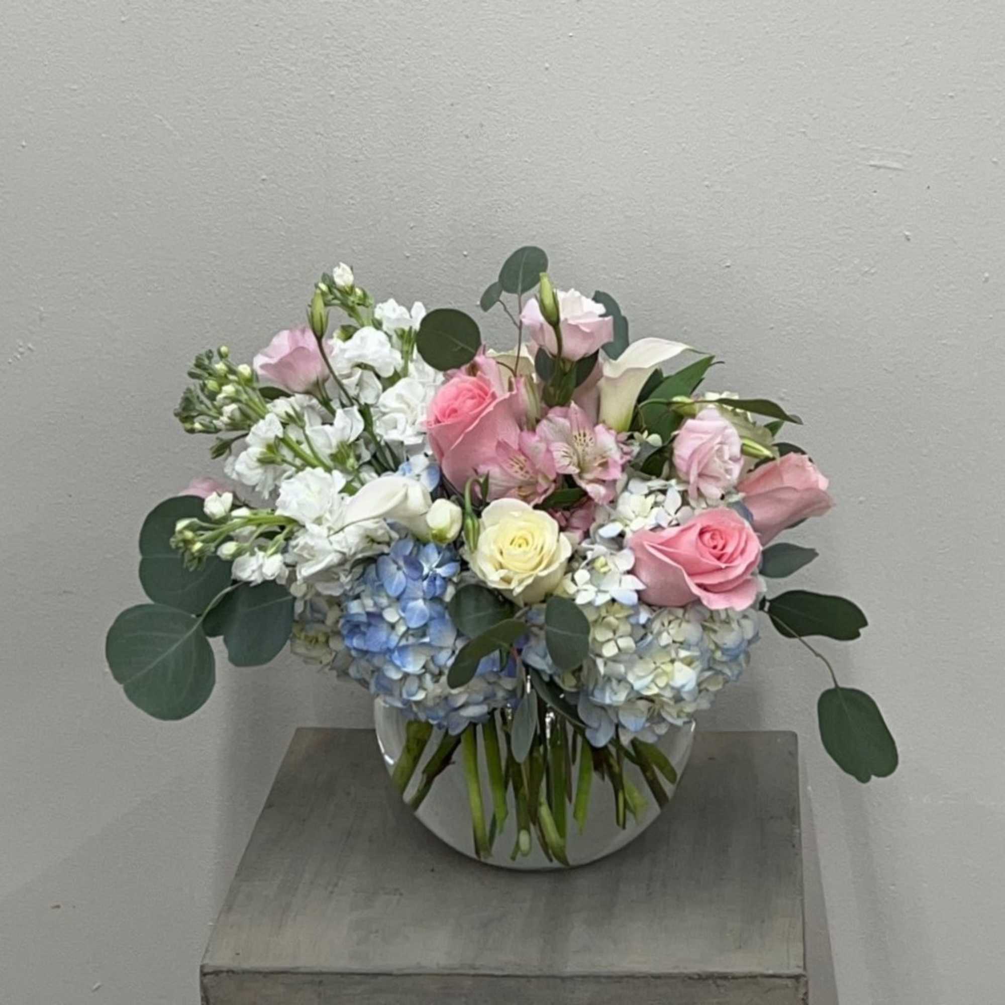 Pink and white floral arrangement in a round glass vase