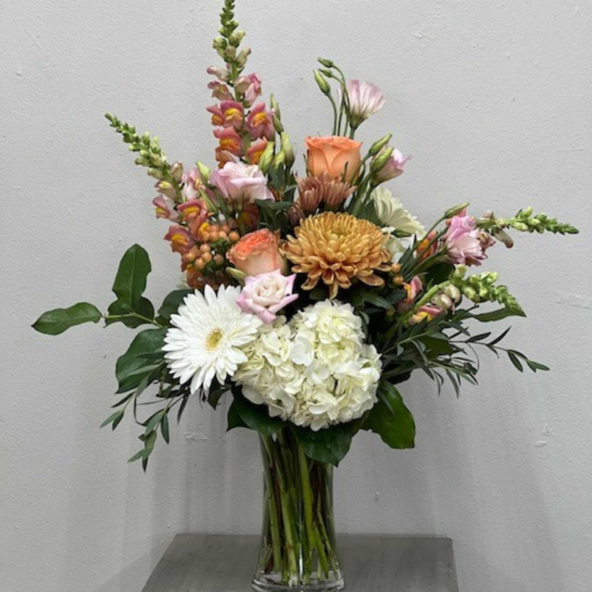 Mixed bouquet in a clear glass vase with white and peach blooms