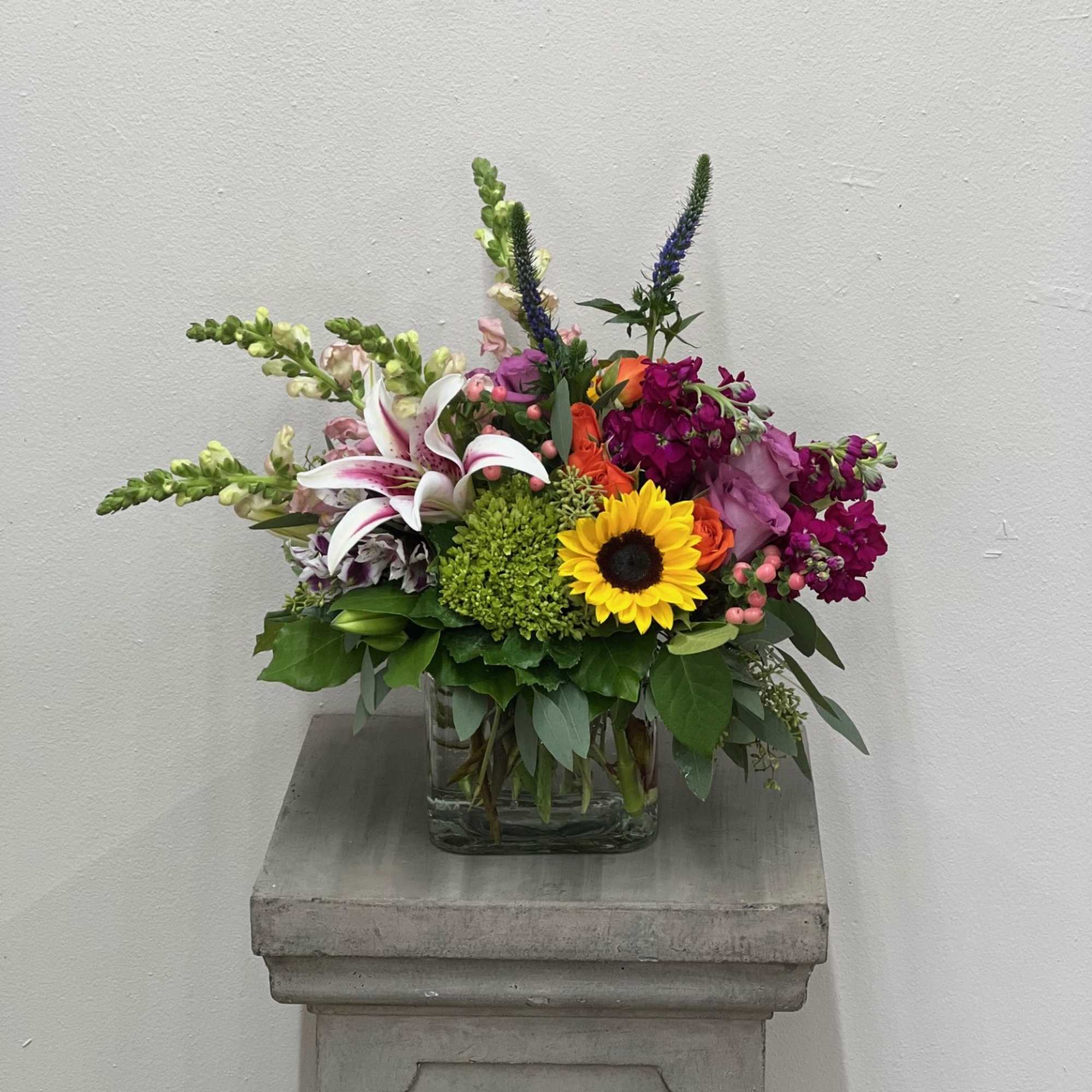 Mixed bouquet in a clear glass vase with a sunflower and lilies