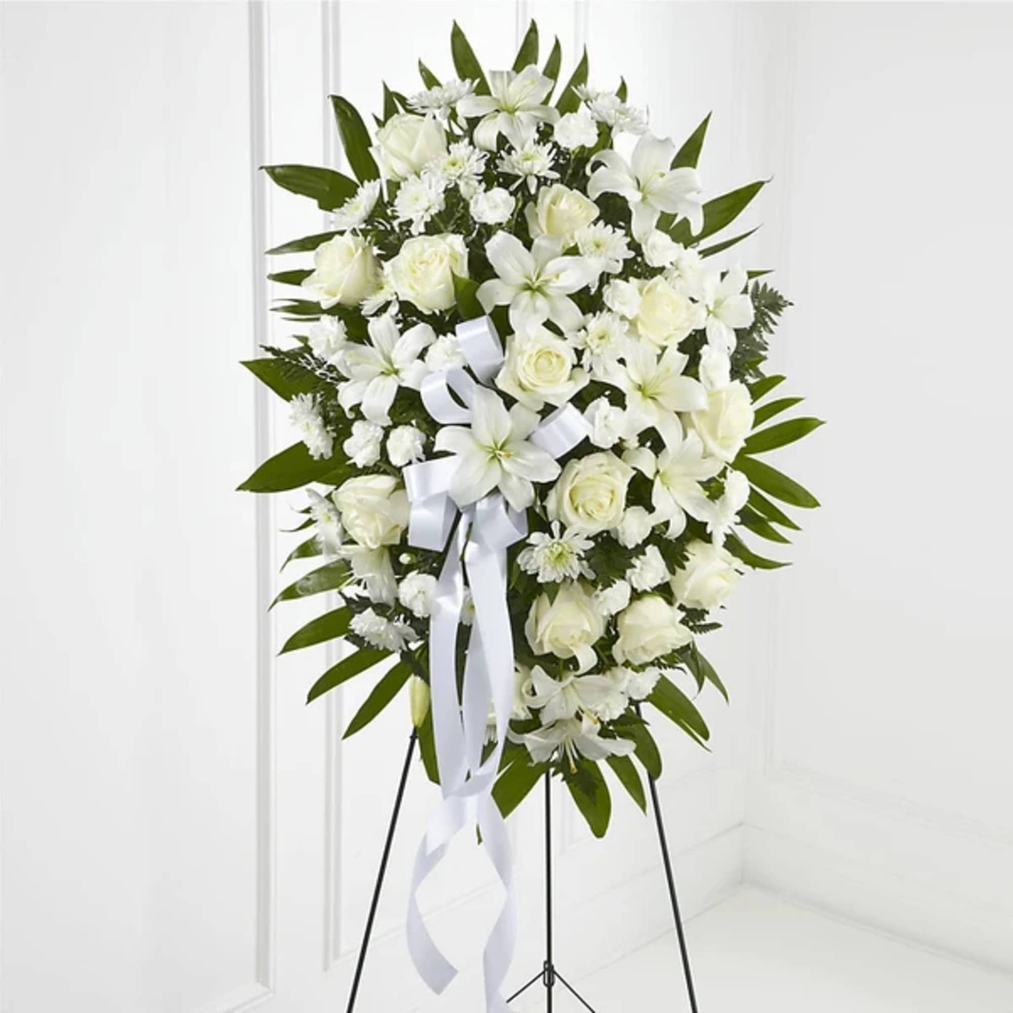 White floral standing spray with roses and lilies on an easel