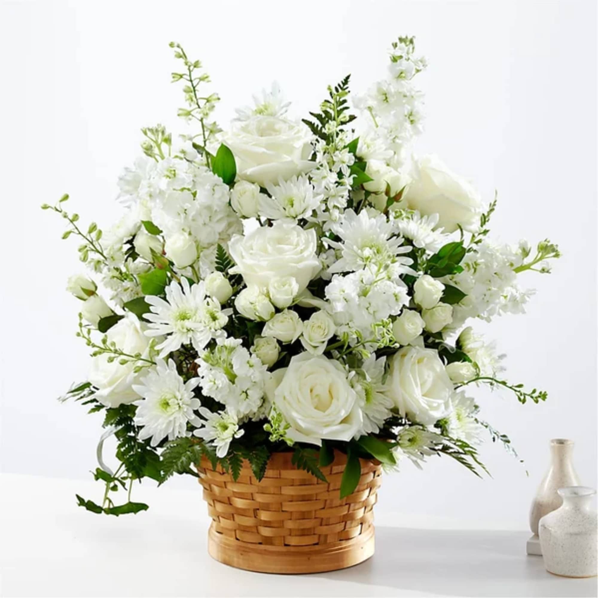 White roses and daisies arranged in a woven basket