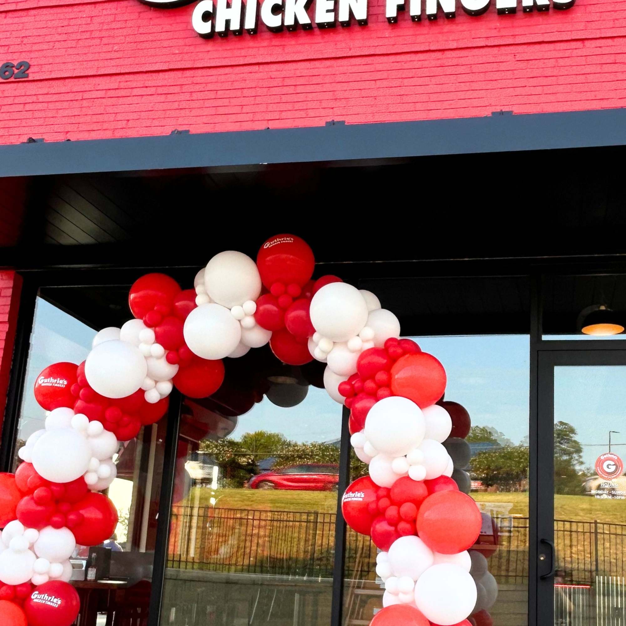 Red and white balloon arch outside a Guthrie's Chicken Fingers storefront