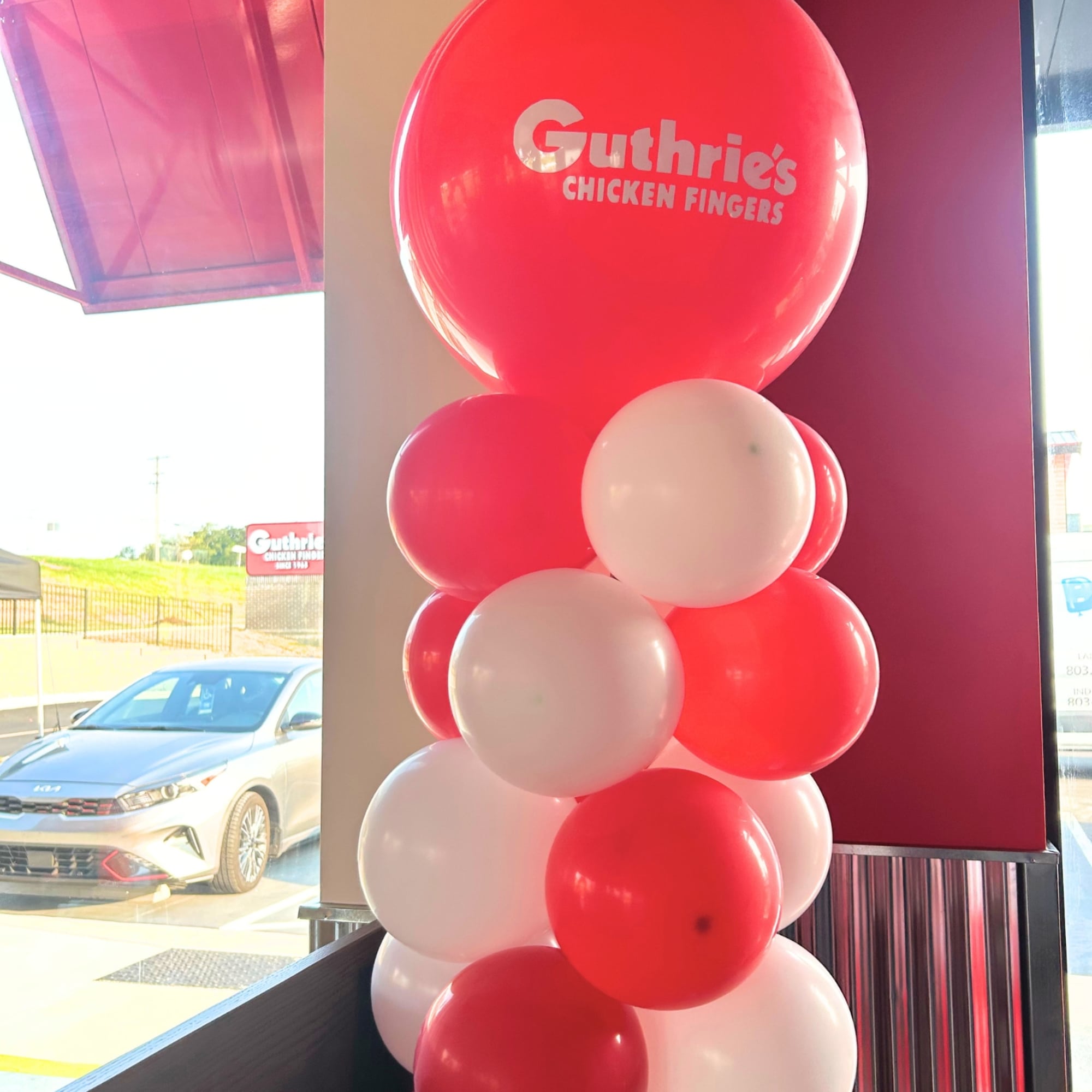 Red and white balloon column with a branded top balloon