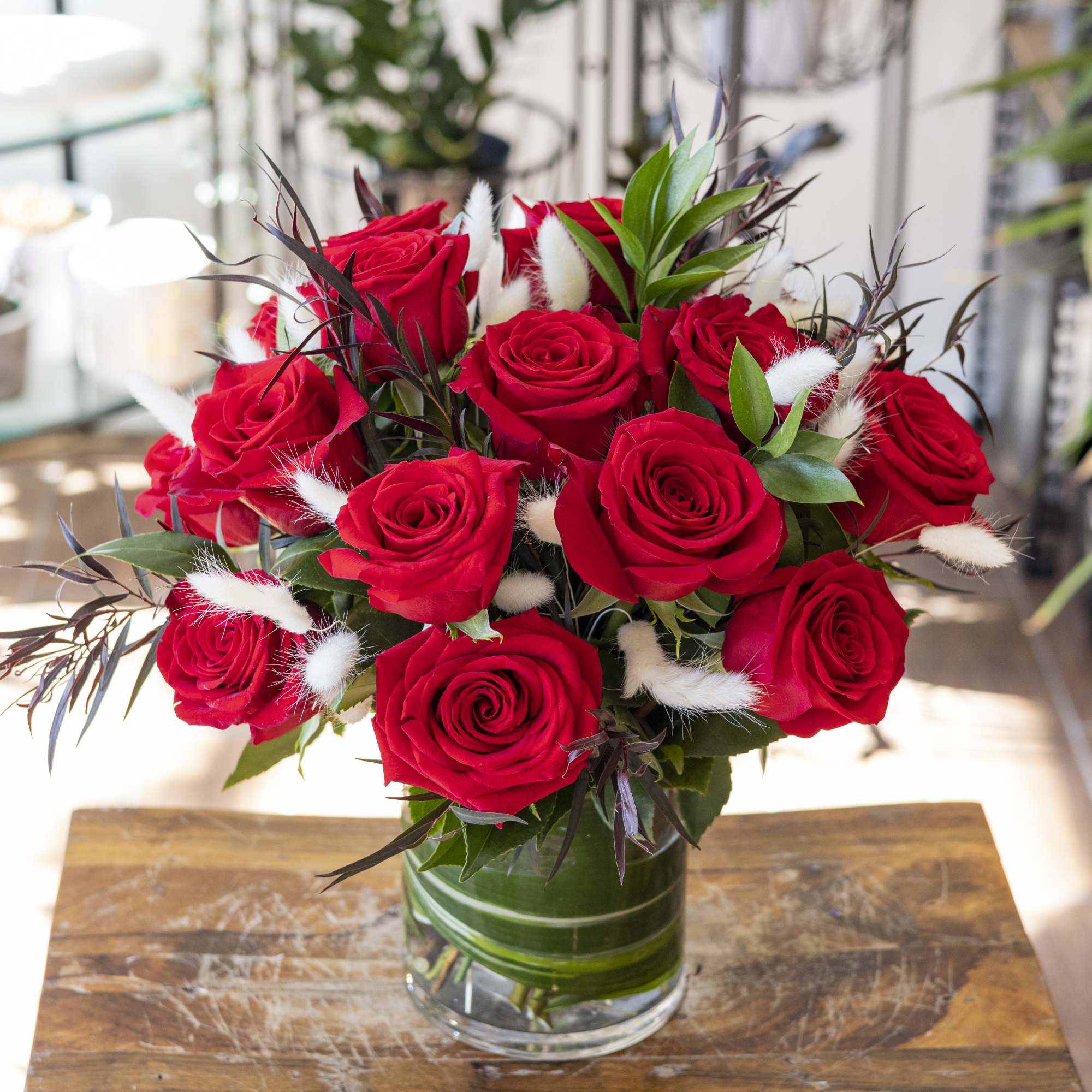 Red roses arranged in a clear glass vase with white accents