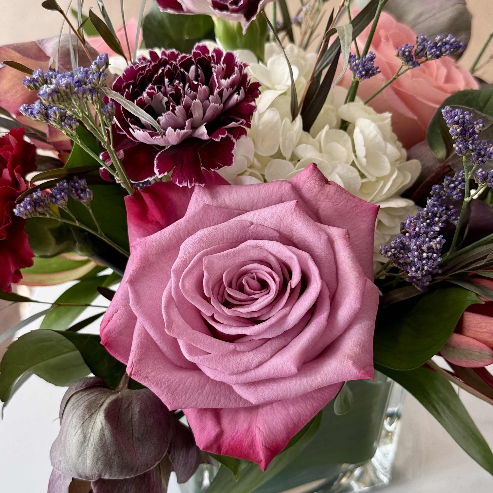 Bouquet with a pink rose, carnations, and white hydrangeas in a glass vase