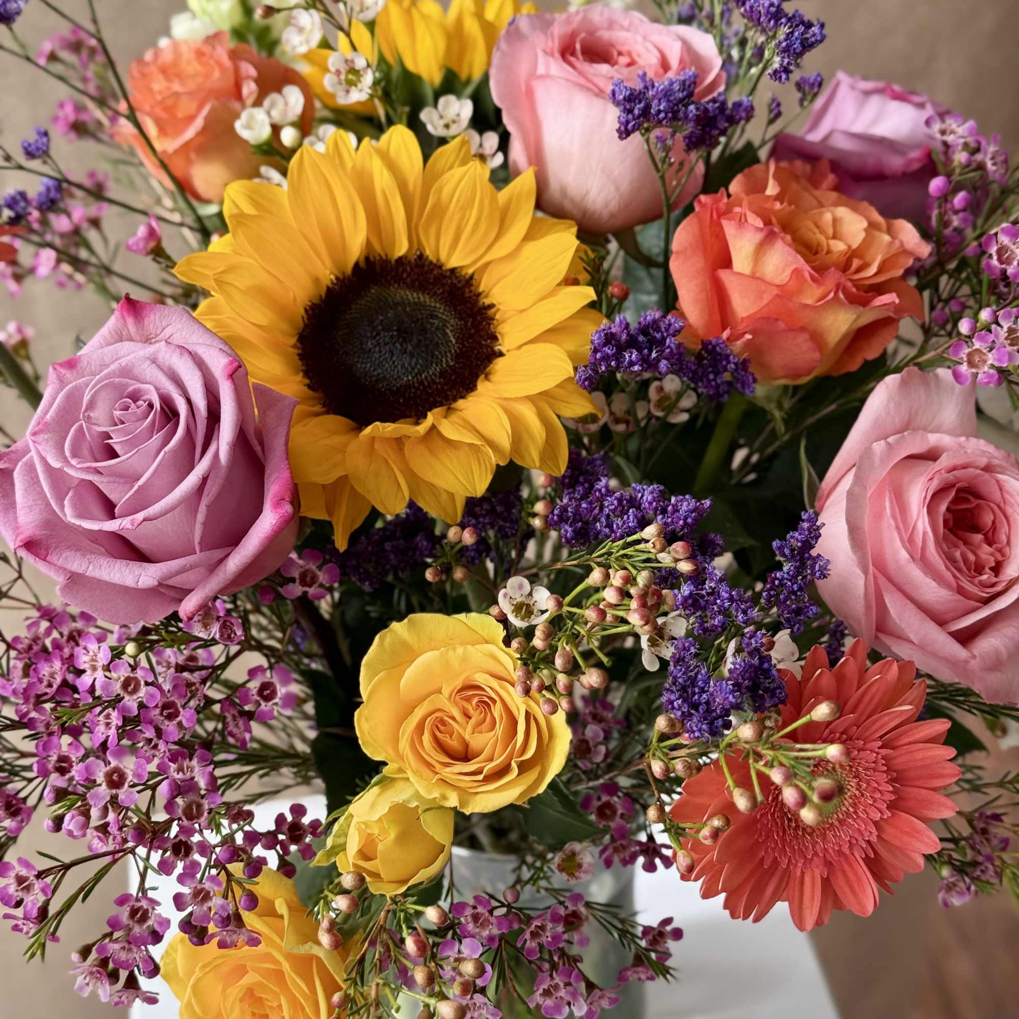 Mixed bouquet with sunflowers, roses, and a gerbera daisy in a glass vase