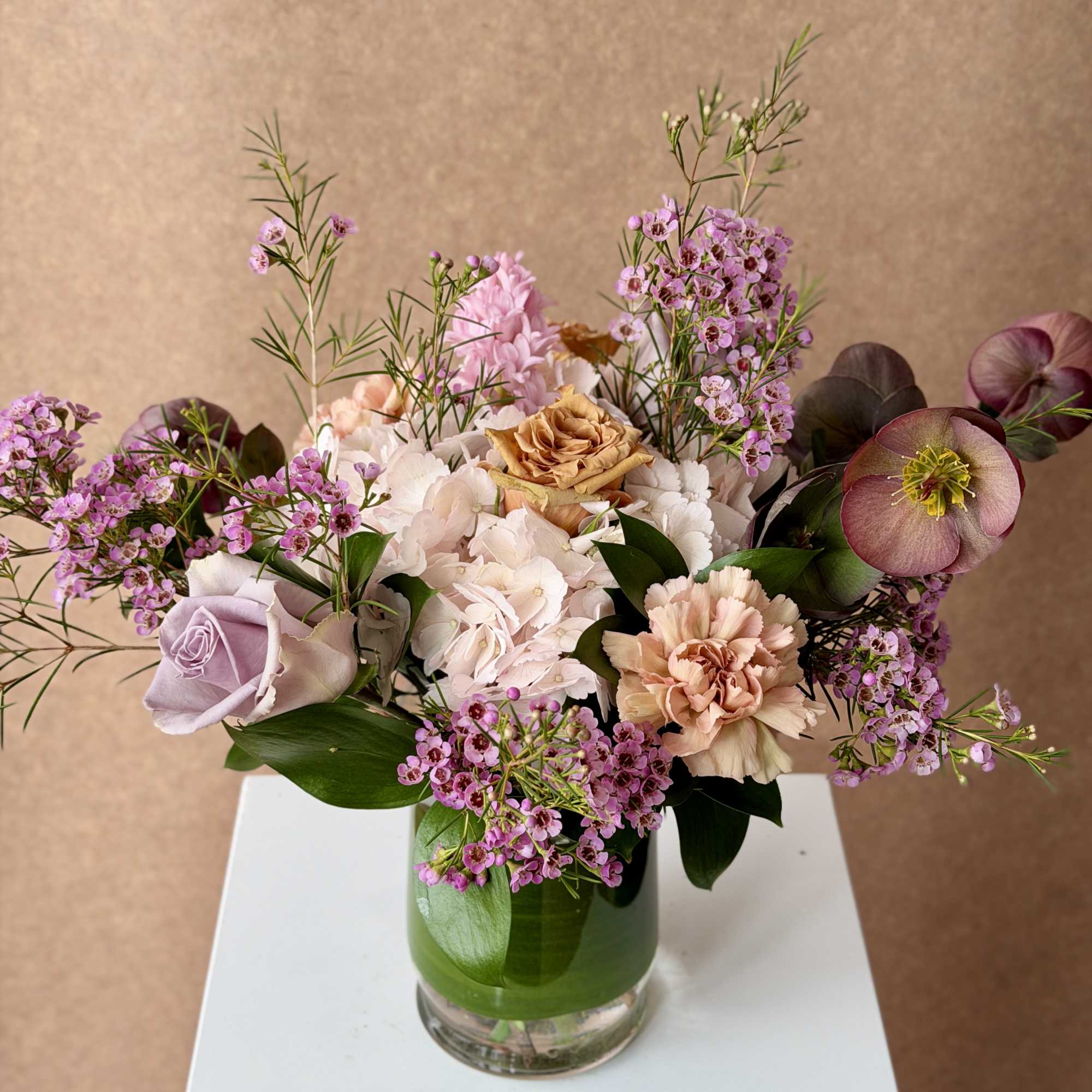 Mixed bouquet of pink and cream flowers in a glass vase