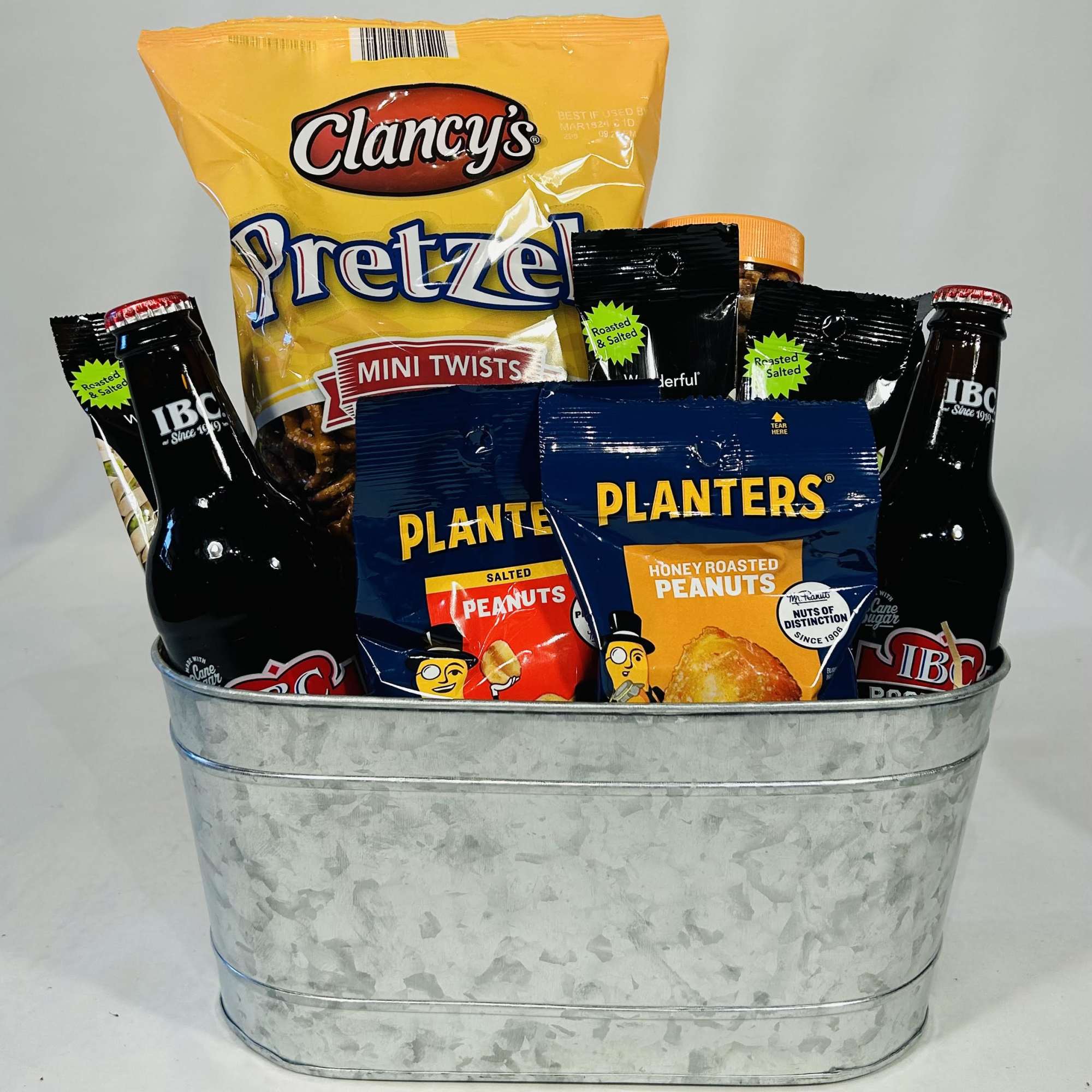 Gift basket with pretzels, peanuts, and bottled drinks in a metal tub
