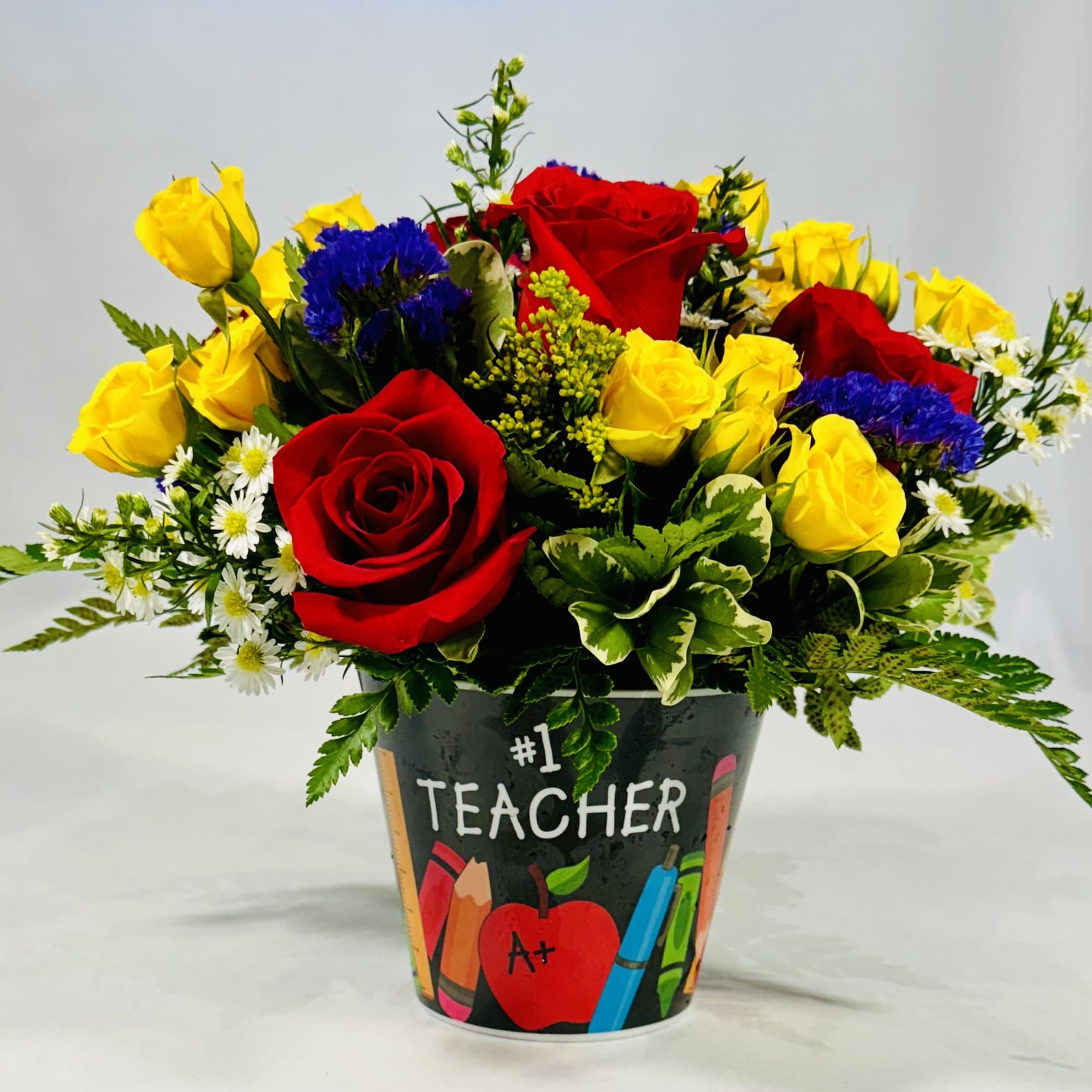 Bouquet of red and yellow roses in a teacher-themed container