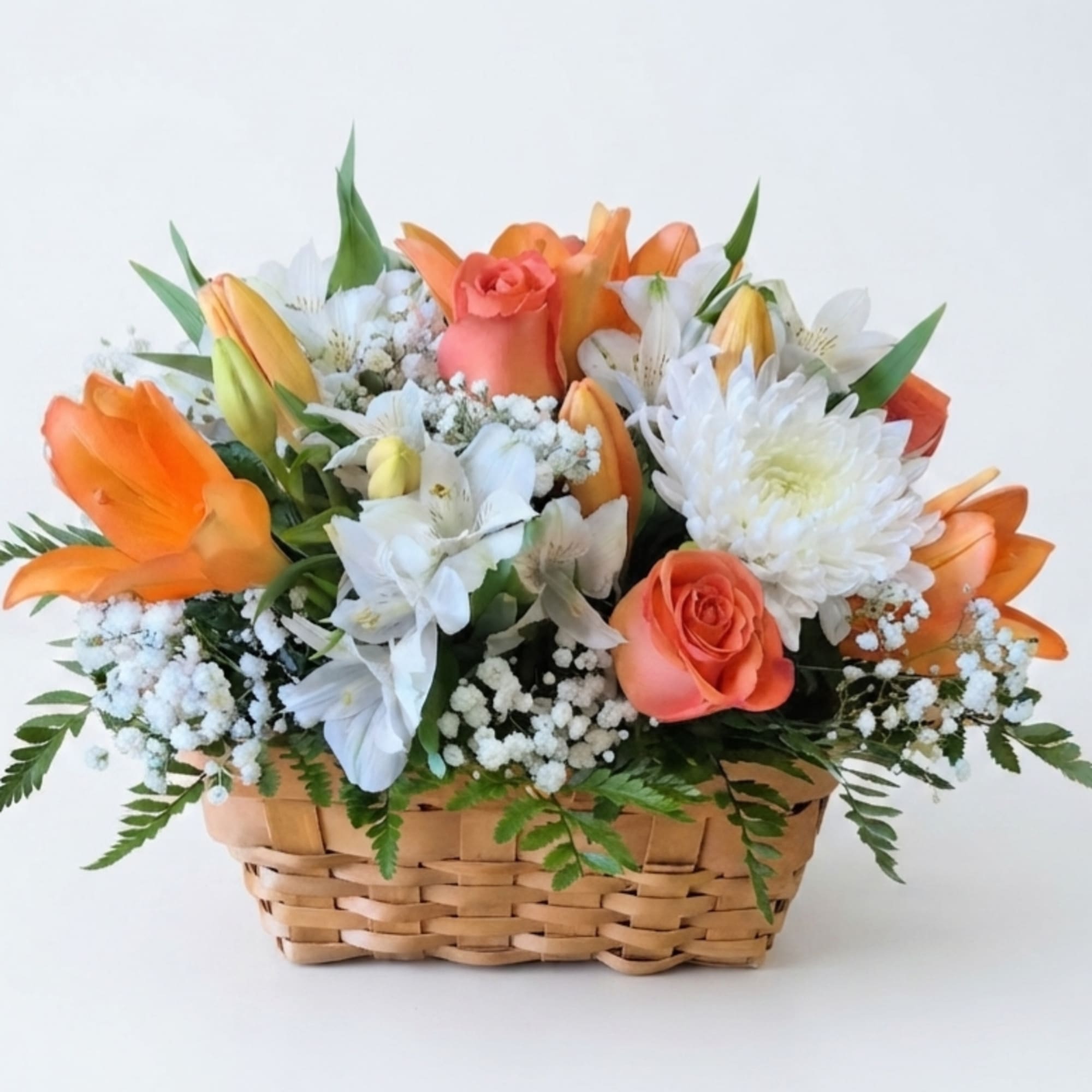 Basket arrangement of orange roses, white flowers, and lilies