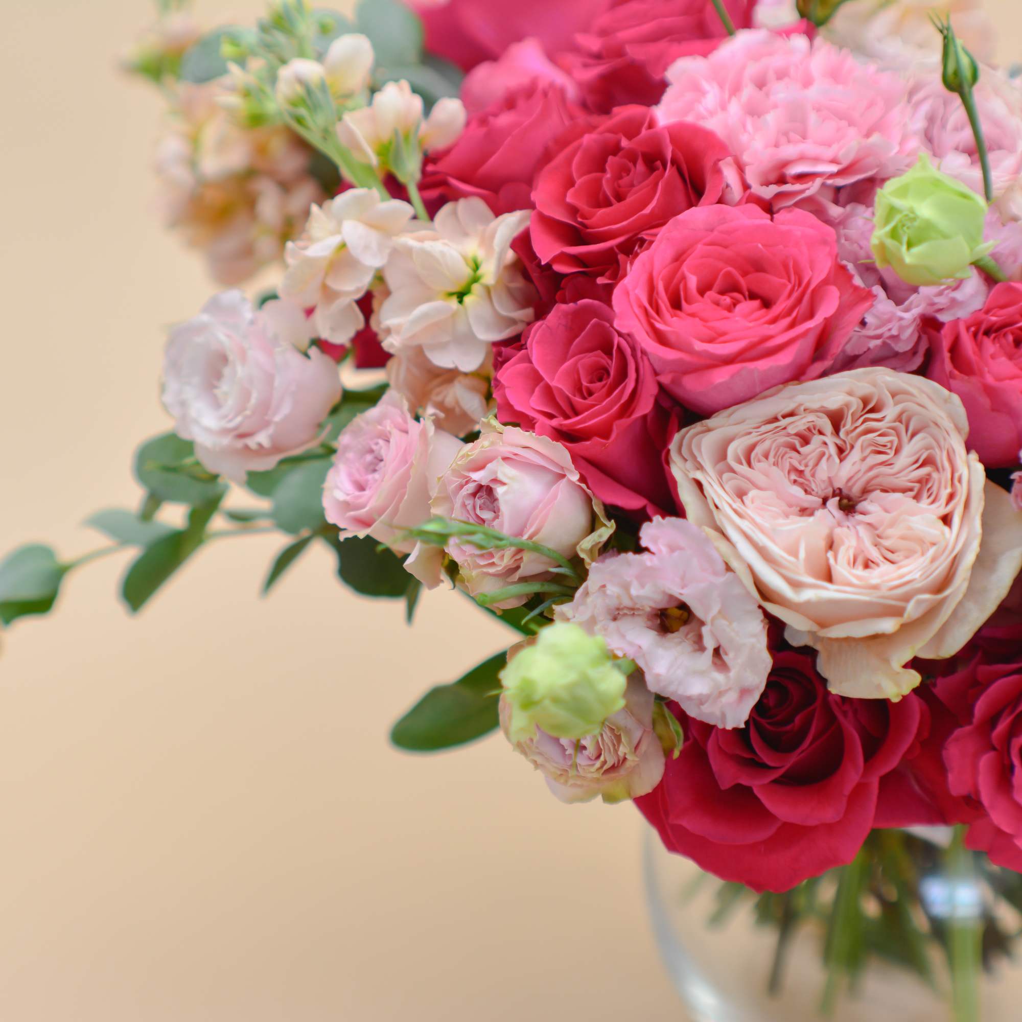 Pink and red roses with pale pink filler flowers in a glass vase