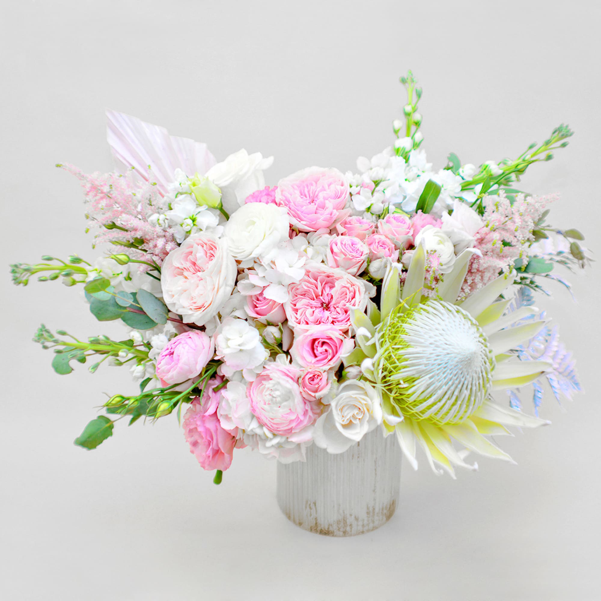 Pink and white bouquet in a white vase with a large pale protea bloom