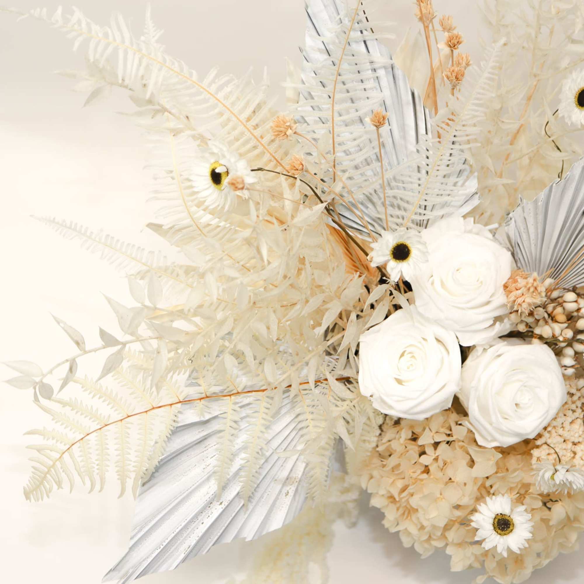 White roses and daisy-like blooms in a pale dried arrangement