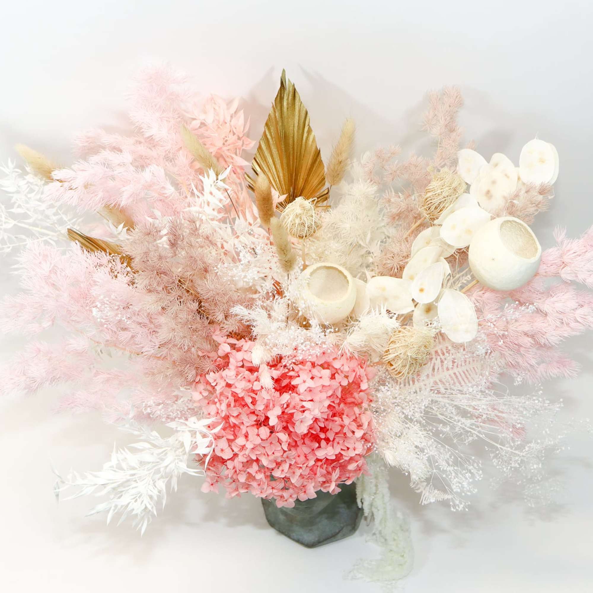 Pink and white dried floral arrangement in a dark vase