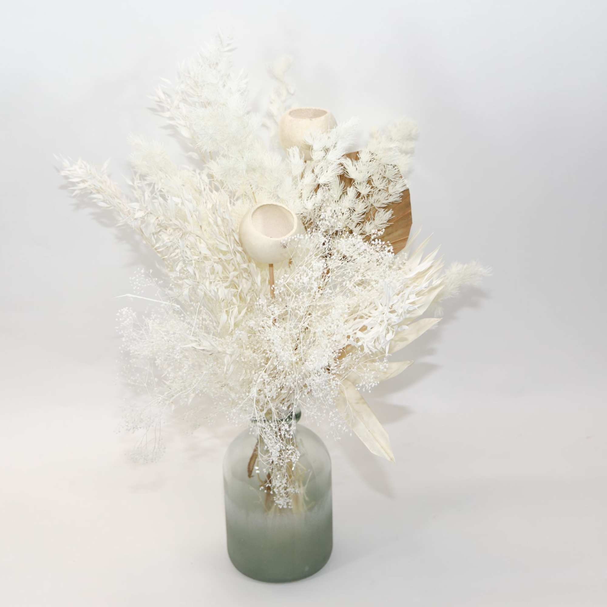 White dried floral arrangement in a frosted glass vase