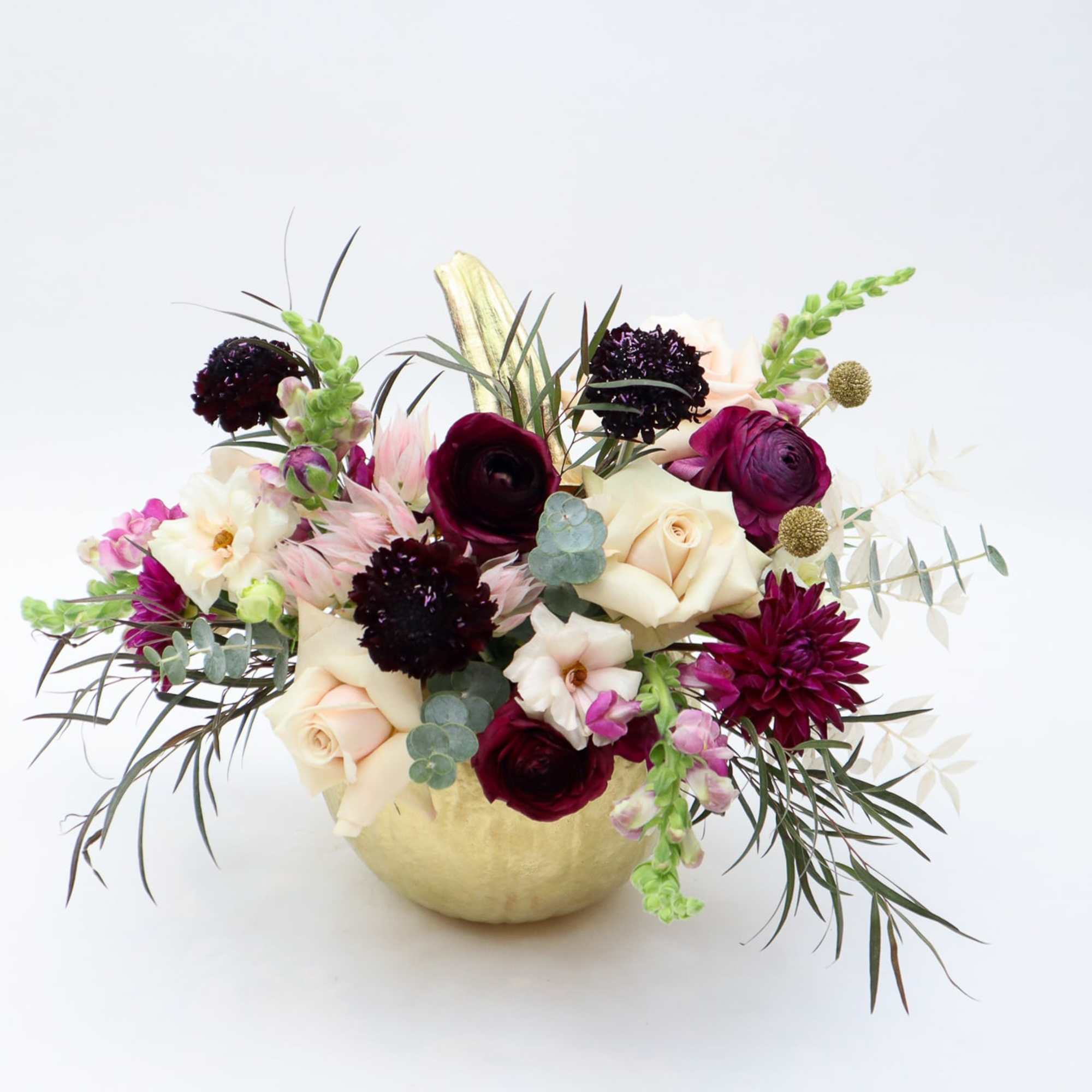 Mixed bouquet in a gold vase with cream, burgundy, and pink flowers